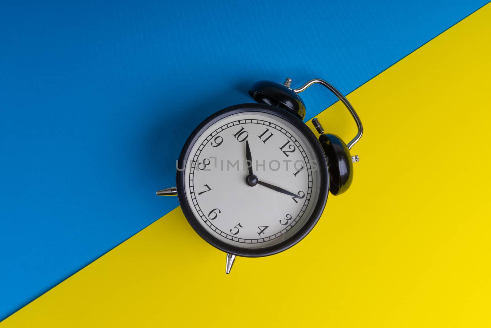 Alarm clock on a blue and yellow background. Business Concept