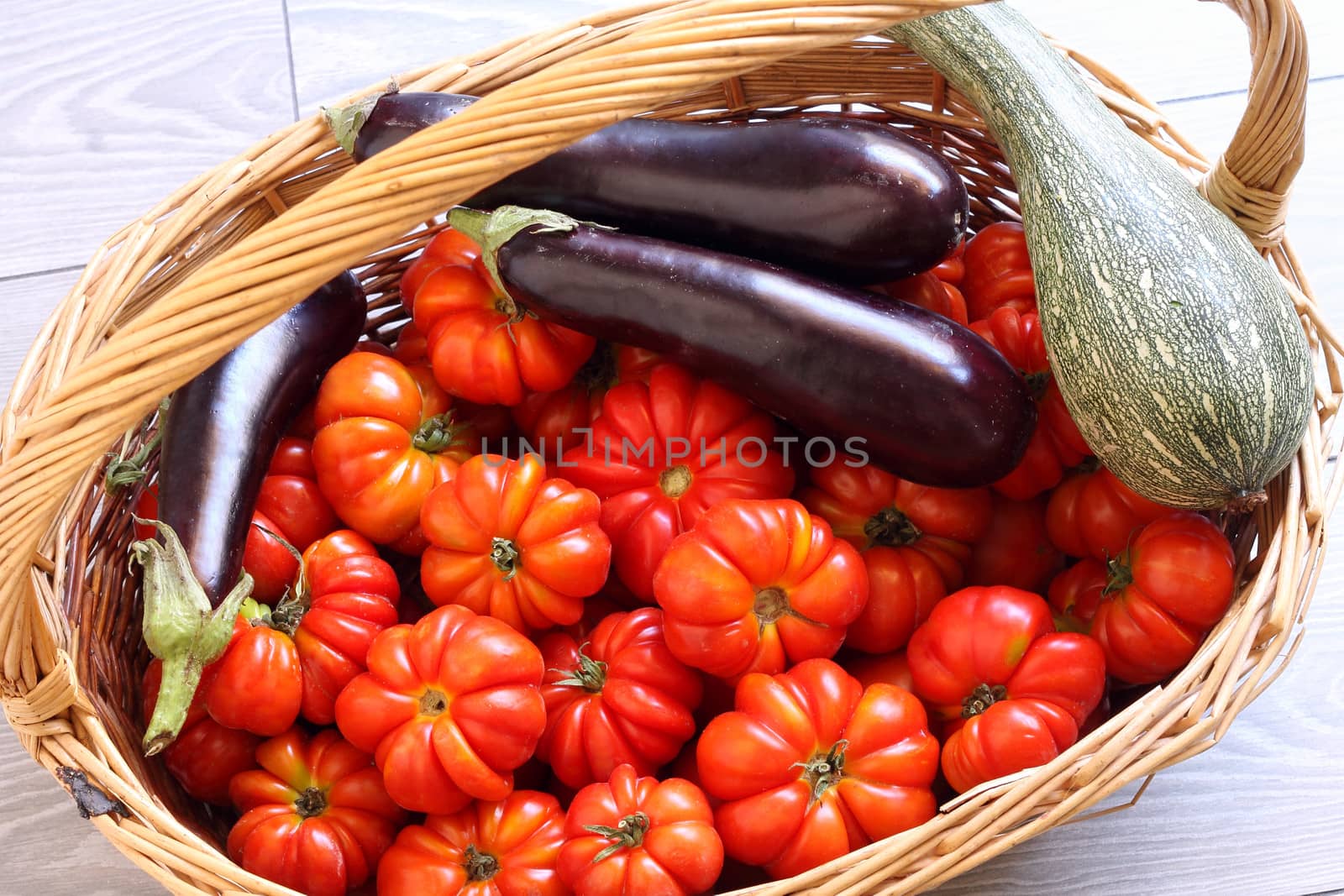 Organic tomatoes, eggplant and pumpkin in wicker basket