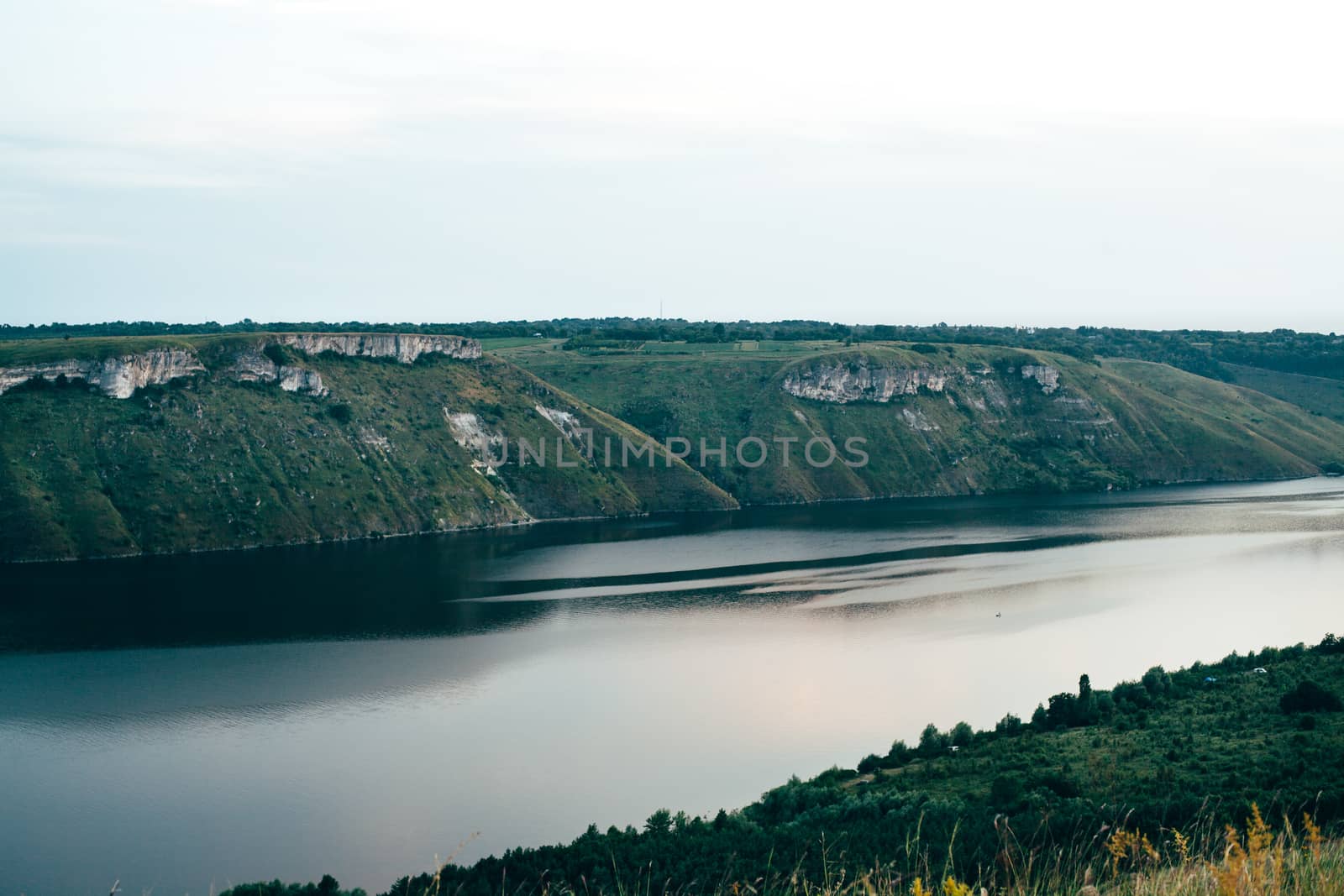 A large river on a background of rocky hills covered with trees.