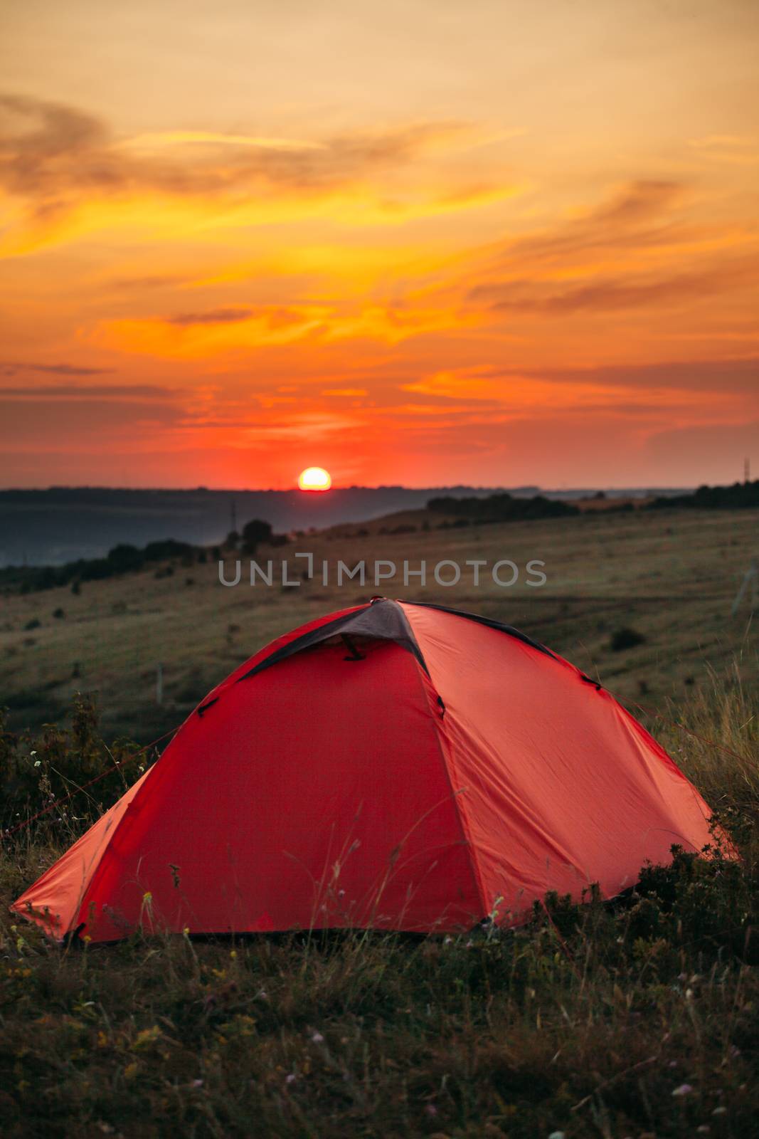 Orange tent at sunset in the mountains. Camping in nature.