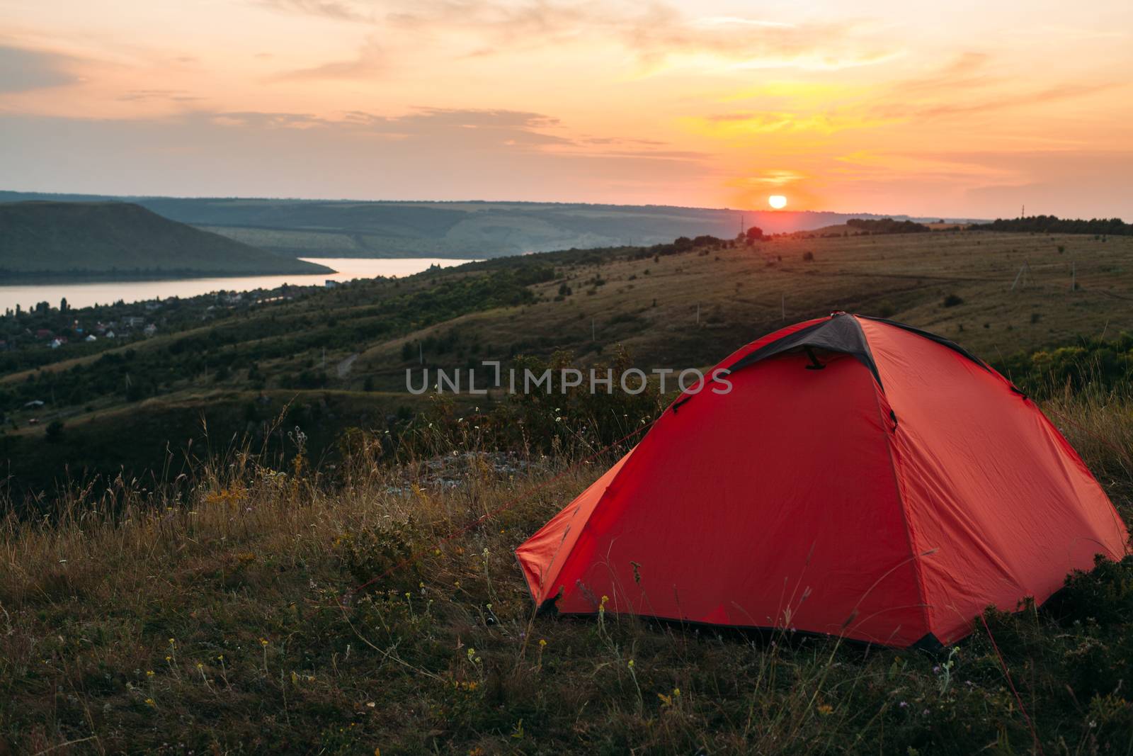 Orange tent at sunset in the mountains. Camping in nature.