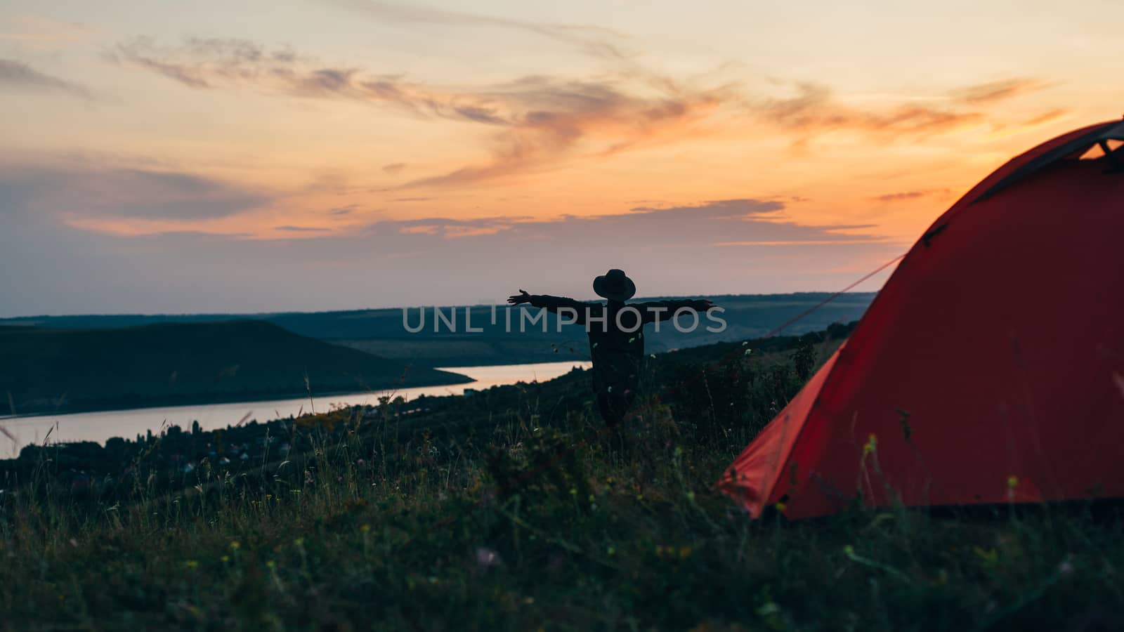 Girl near the tent at sunset with hands up.
 by Opikanets