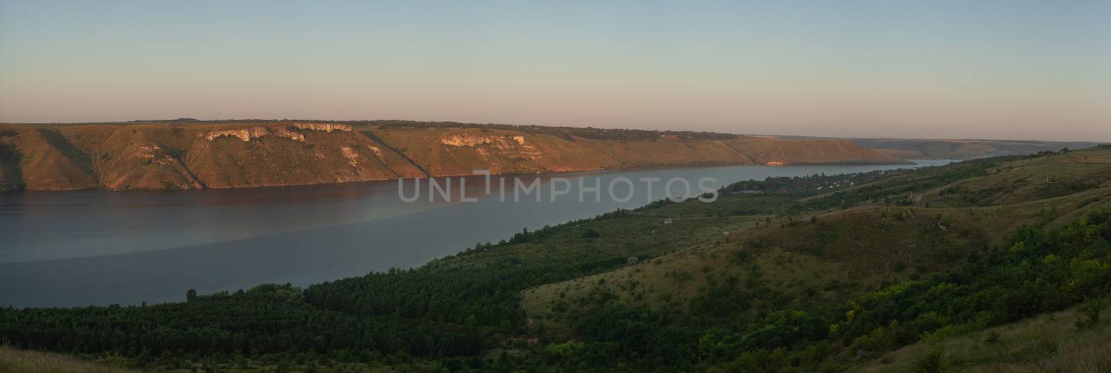 A large river on a background of rocky hills covered with trees.