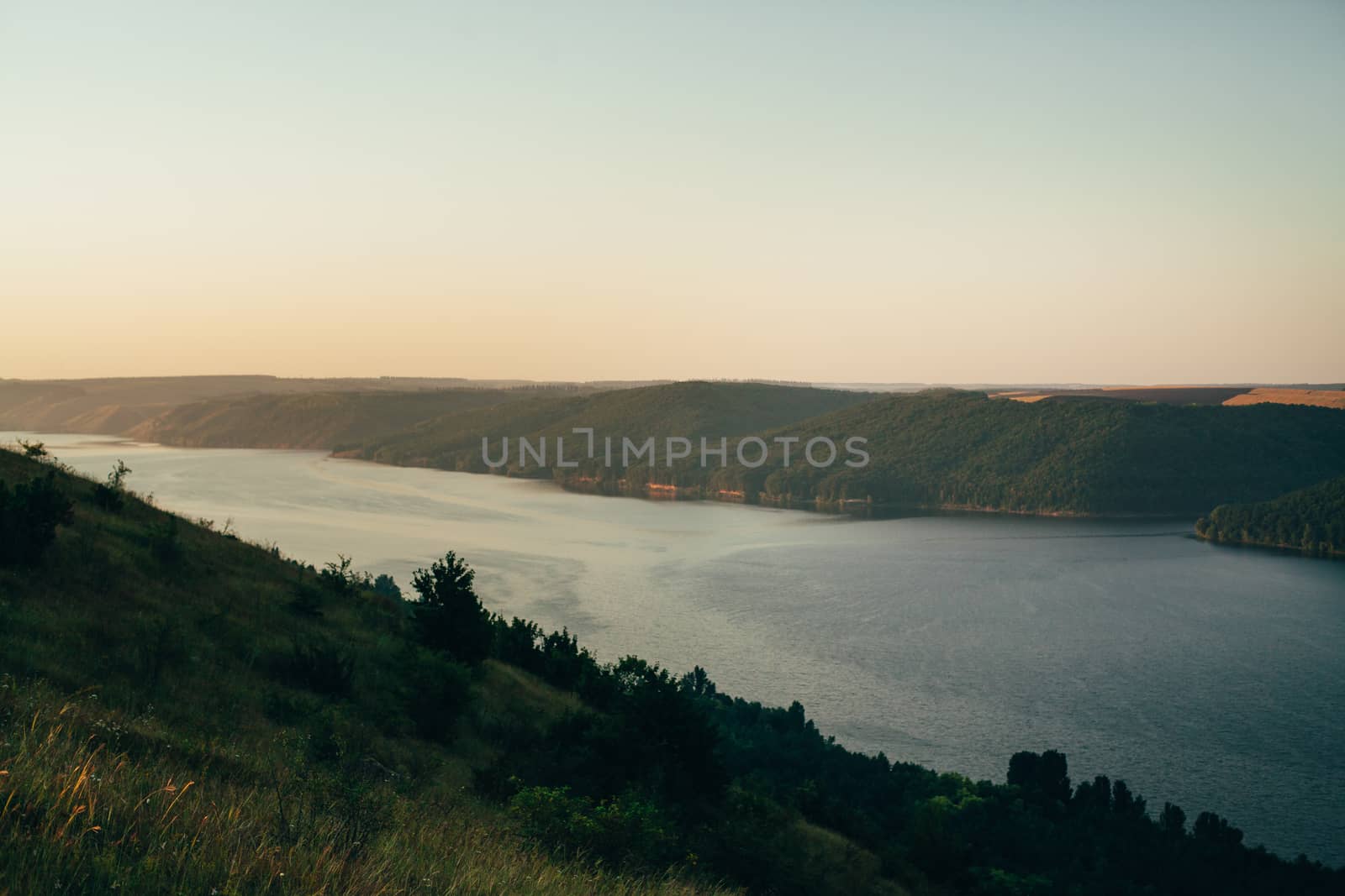 A large river on a background of rocky hills covered with trees.