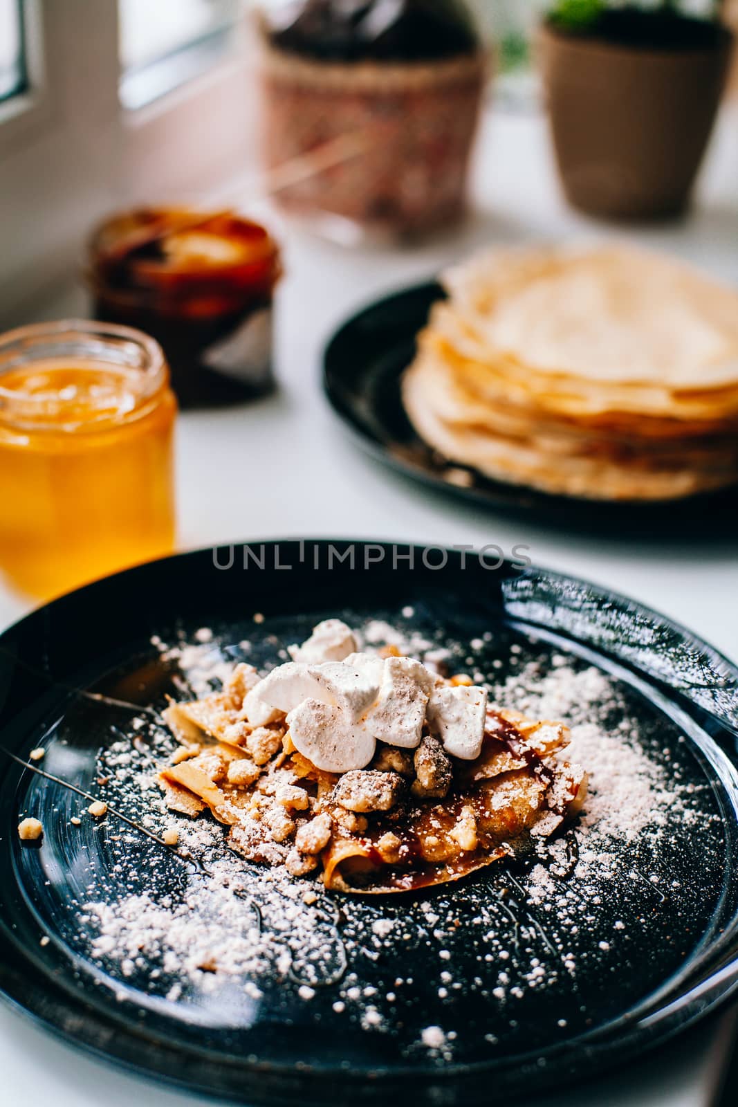 Pancakes with caramel nuts and marshmallows on the kitchen windo by Opikanets