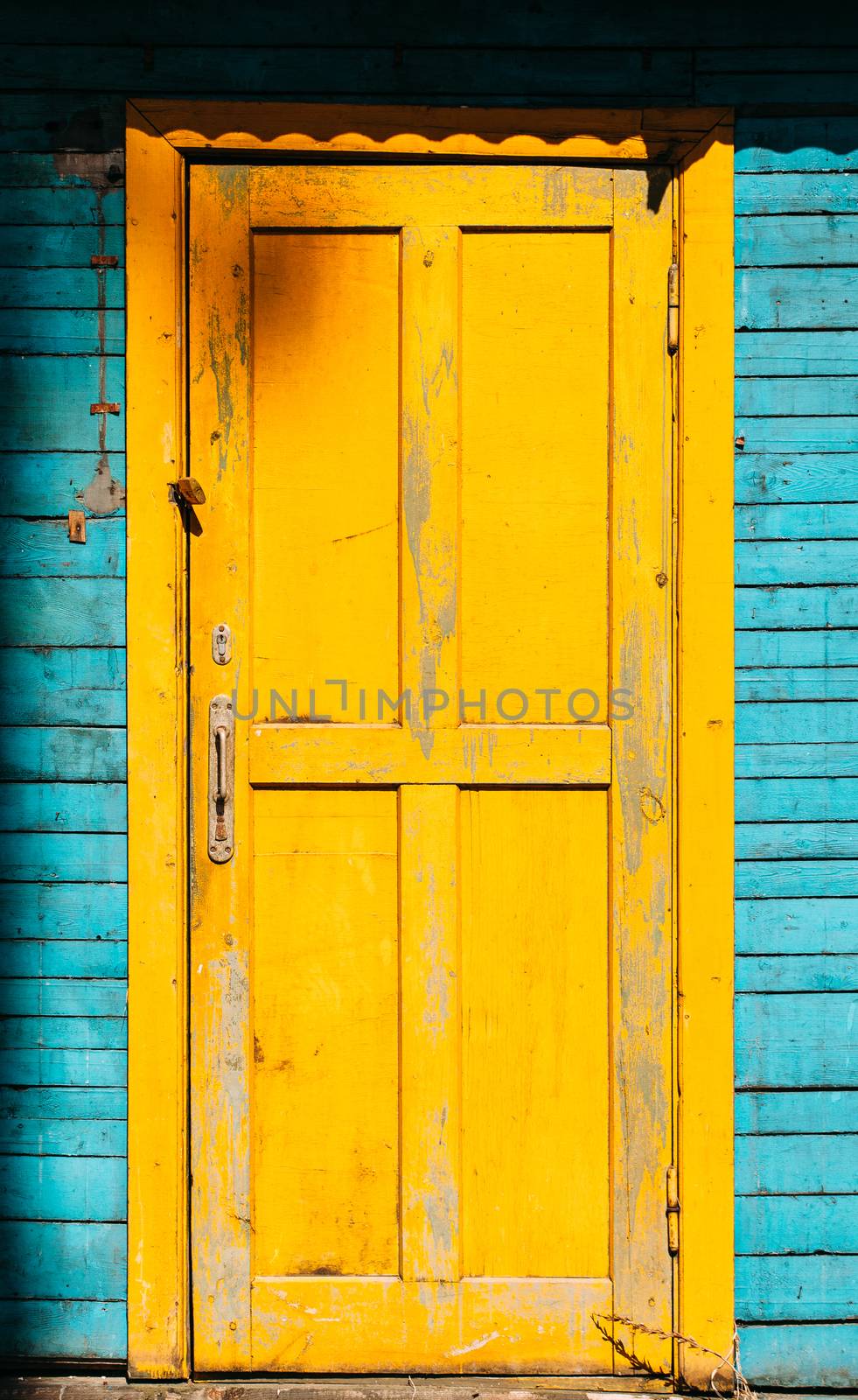 Old wooden doors of yellow color on a blue wooden house. The wall of a treehouse in the forest