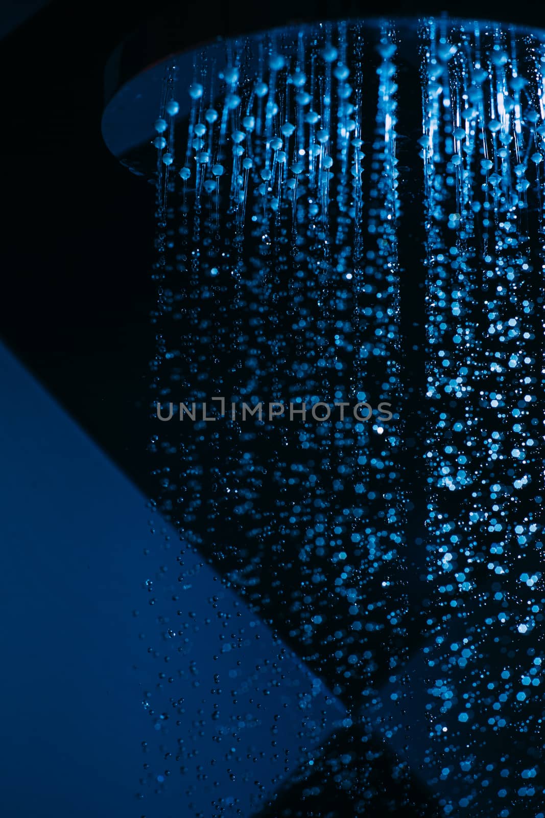 Drops of water fall from a watering can in the shower in blue li by Opikanets