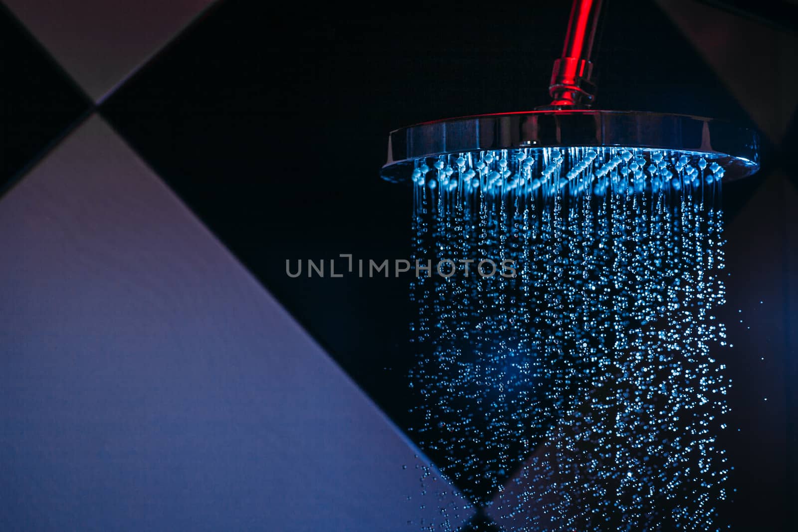Drops of water fall from a watering can in the shower in blue light. Water drops close-up. Flow of water. Big round watering can.