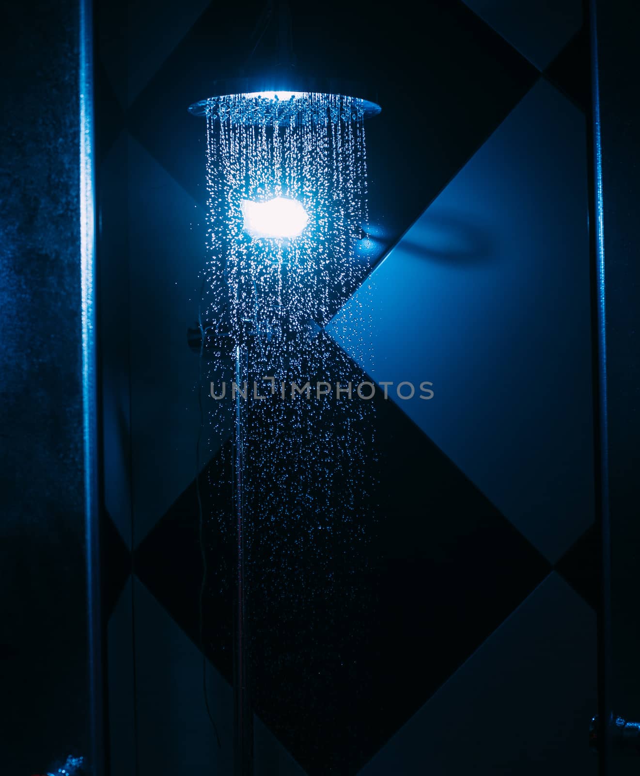 Drops of water fall from a watering can in the shower in blue li by Opikanets