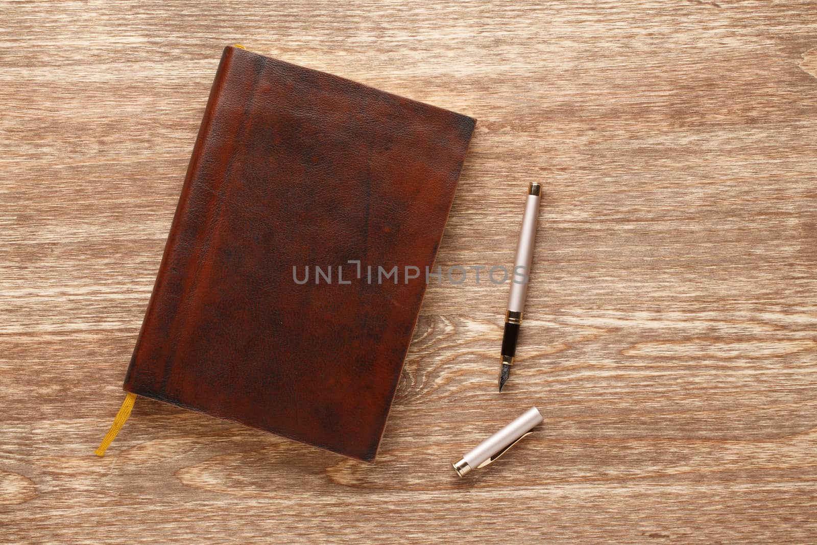 Leather red notebook with fountain pen on a wooden background.