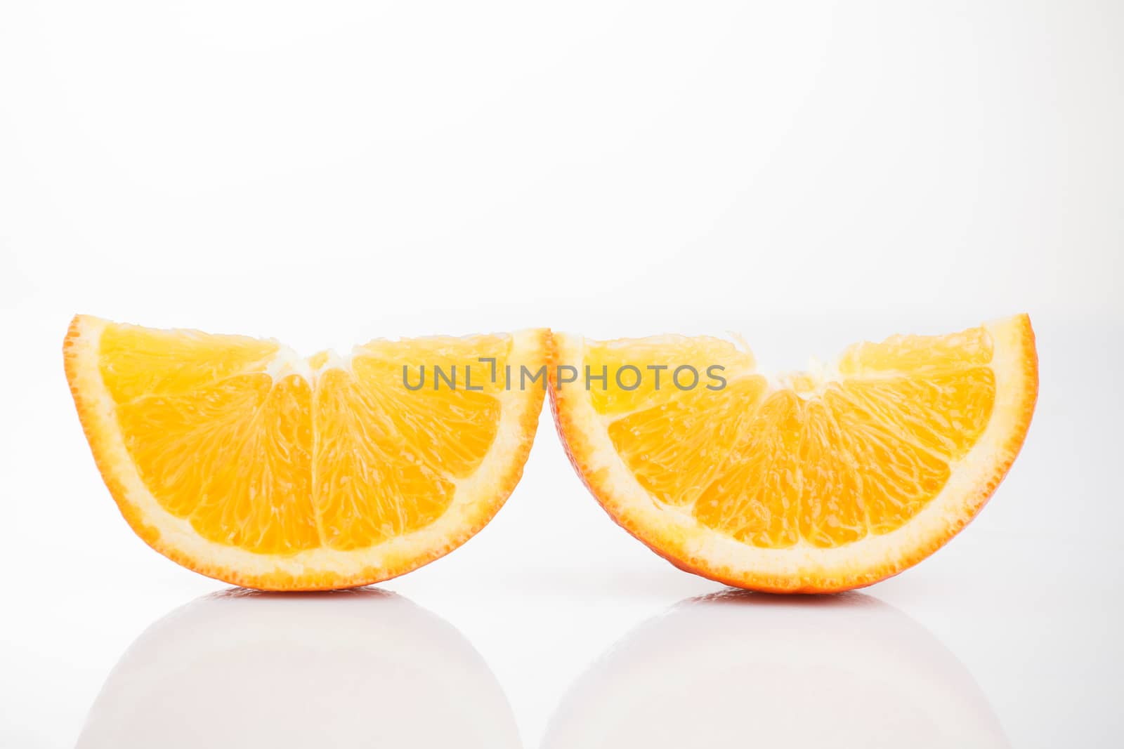 Two slices of sliced ​​orange on a white background with reflection at the bottom. Isolated photo of citrus