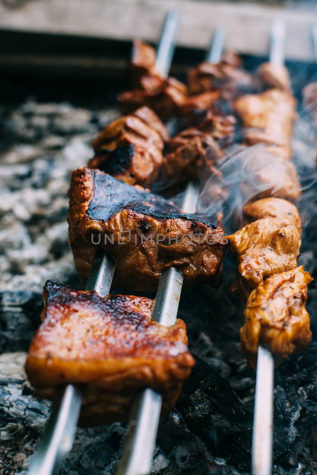 Skewers of pork ribs on a skewer in smoke. Cooking meat in nature.