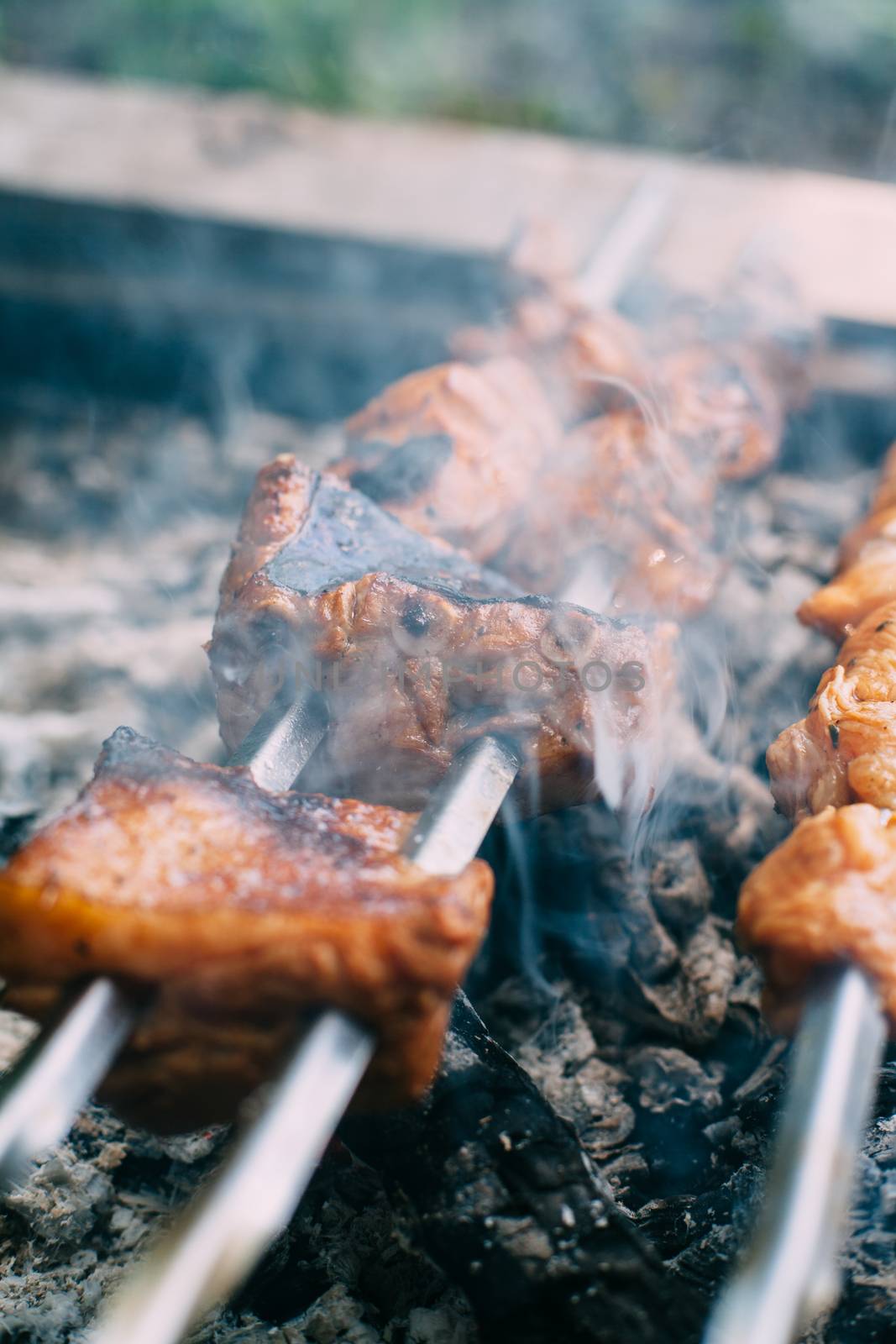 Skewers of pork ribs on a skewer in smoke. Cooking meat in nature.