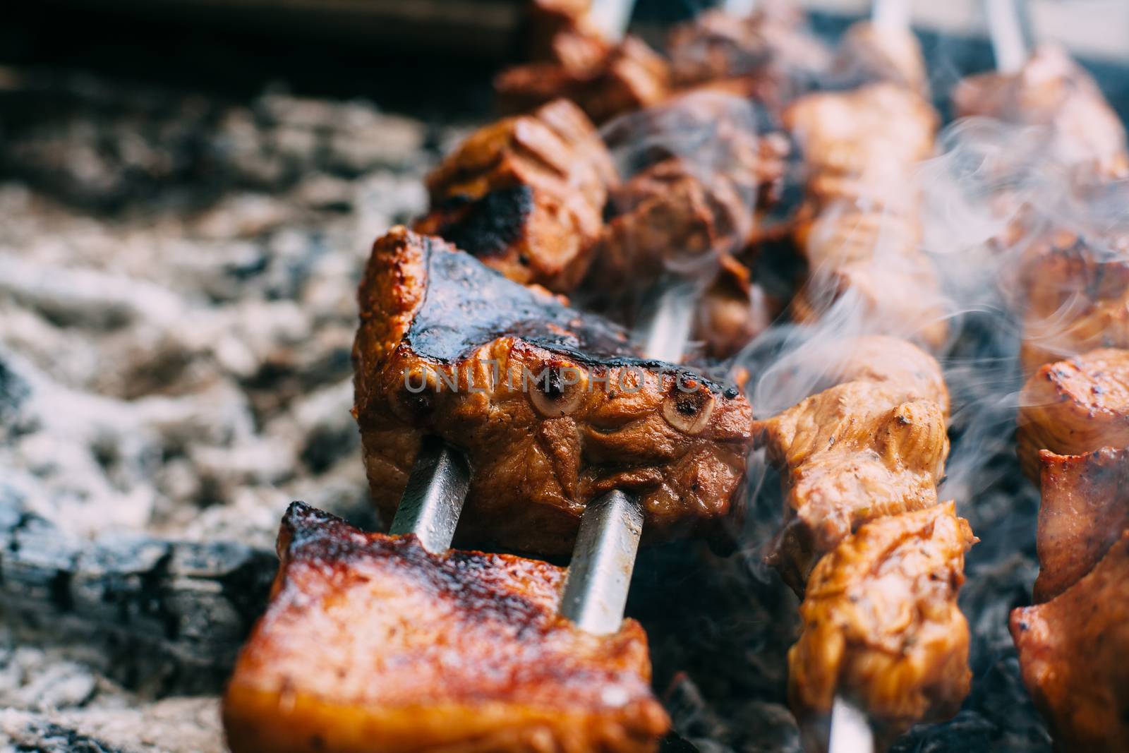 Skewers of pork ribs on a skewer in smoke. Cooking meat in nature.