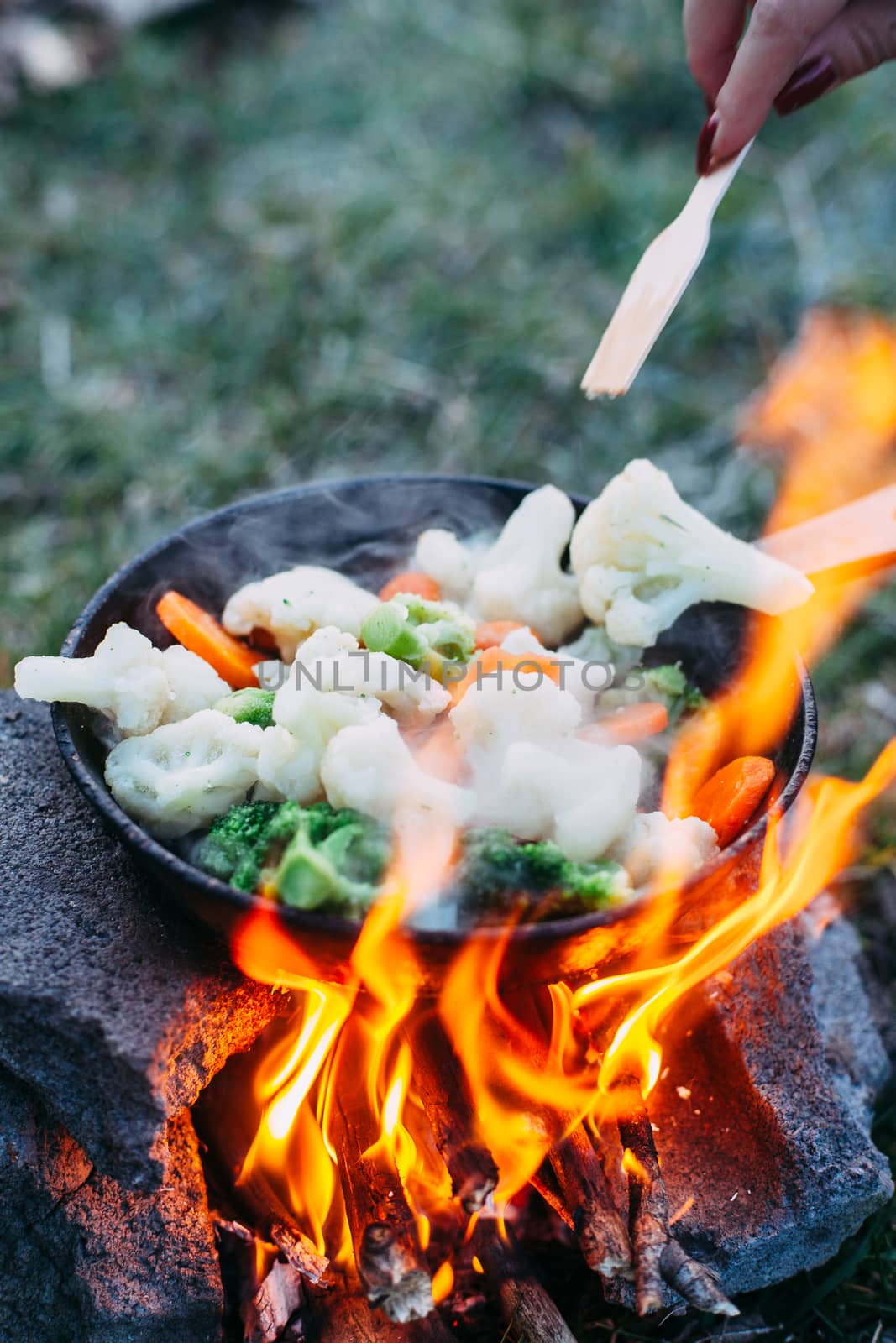 Cauliflower, broccoli and carrot in a pan. Cooking on an open fi by Opikanets