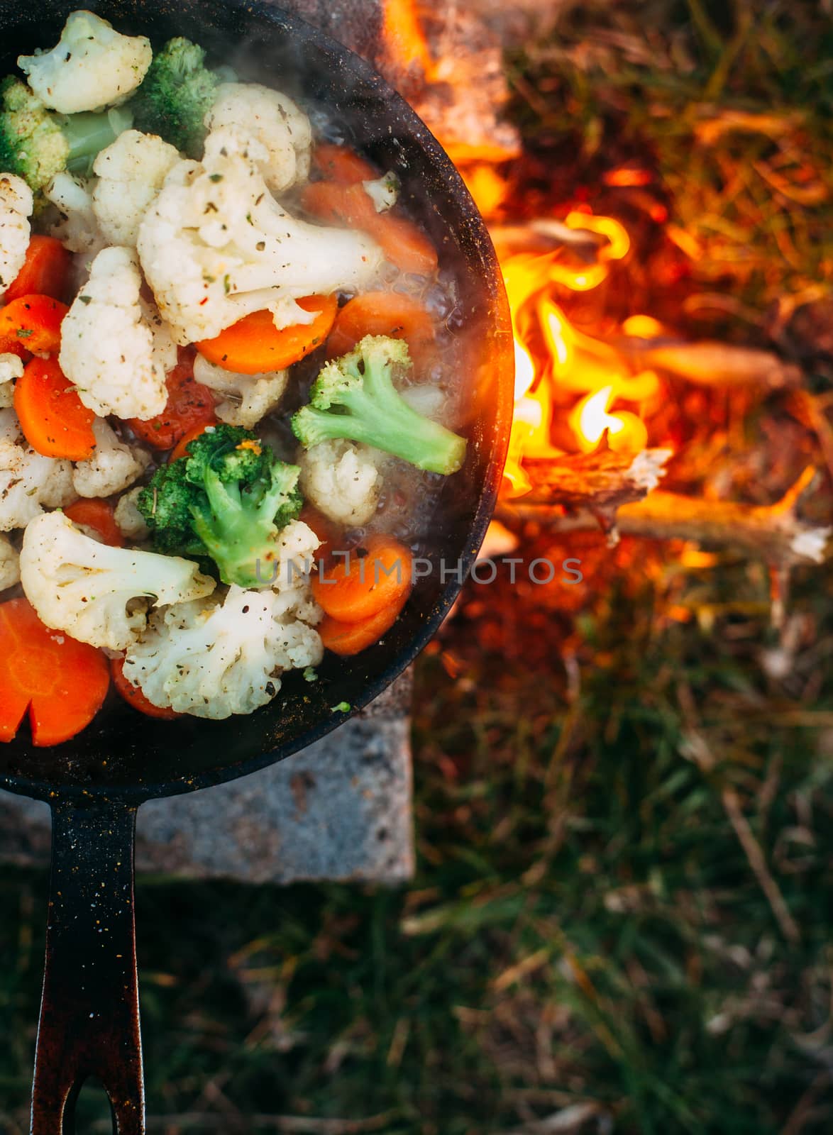 Cauliflower, broccoli and carrot in a pan. Cooking on an open fire. Outdoor food. Grilled vegetables. Food on a camping trip