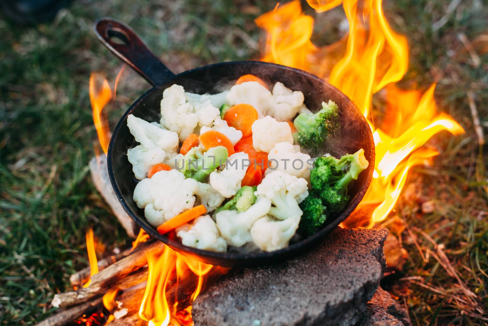 Cauliflower, broccoli and carrot in a pan. Cooking on an open fire. Outdoor food. Grilled vegetables. Food on a camping trip