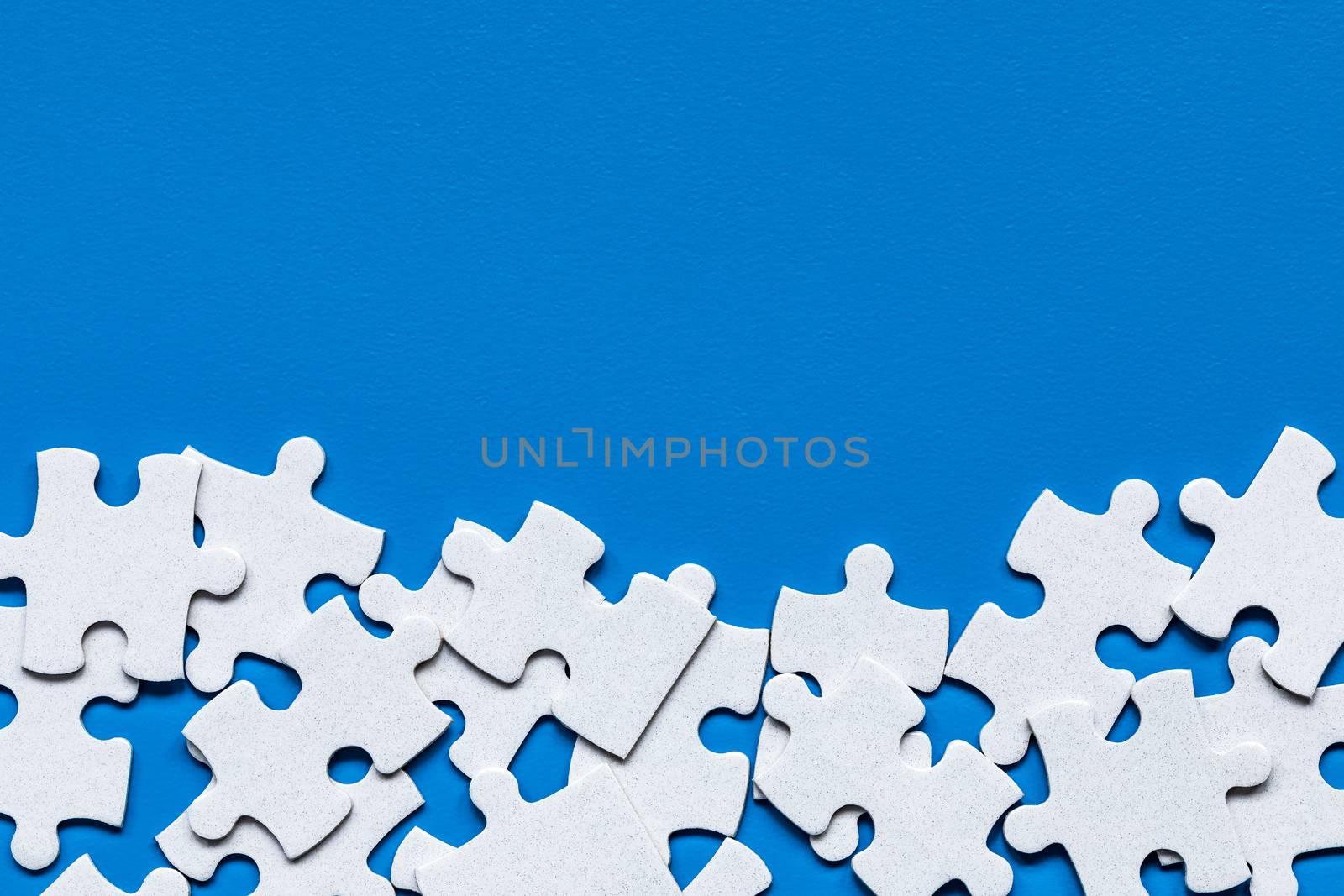White jigsaw puzzle. White puzzle pieces on color background. Unfinished white jigsaw puzzle pieces on color background. 