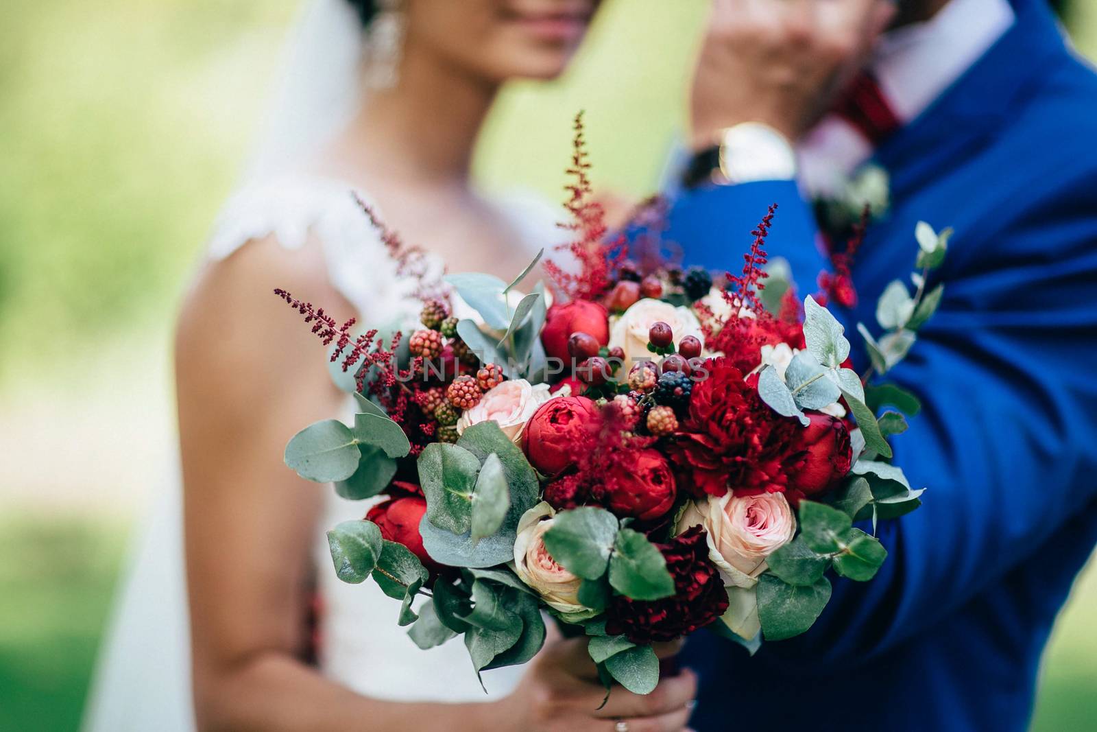 Bouquet in the hand of the bride on the background of a girl and a groom. Bridal bouquet