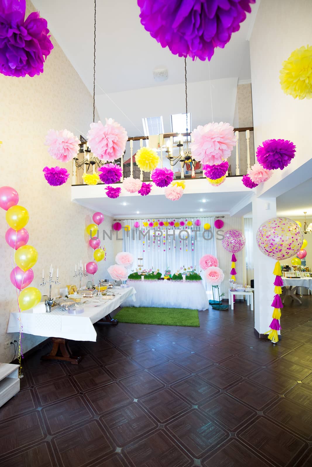 A large room with high ceilings decorated with large balloons and paper pompons for the birthday of the child. Beautifully decorated room interior