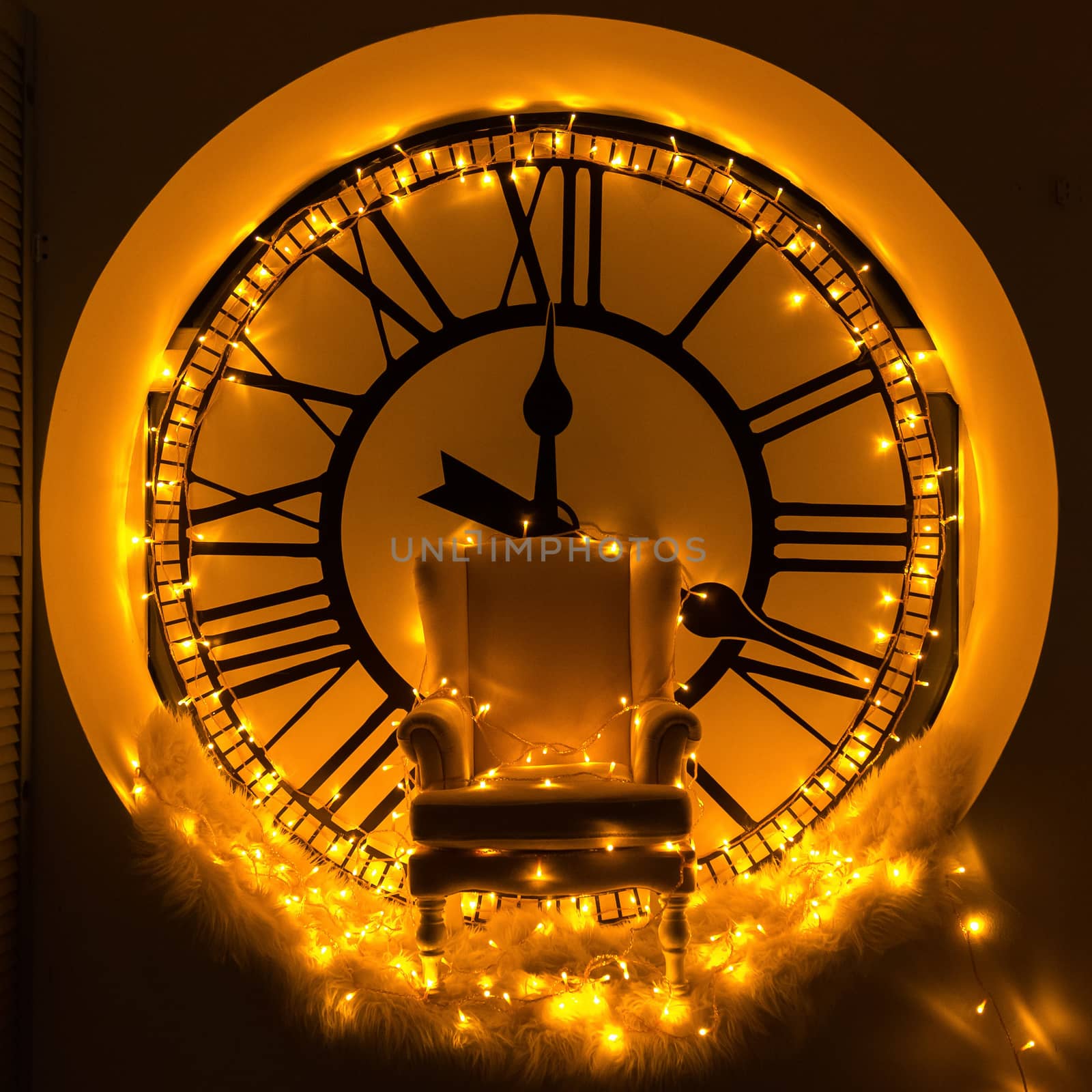 Armchair on the background of a large round clock, decorated with yellow lights.