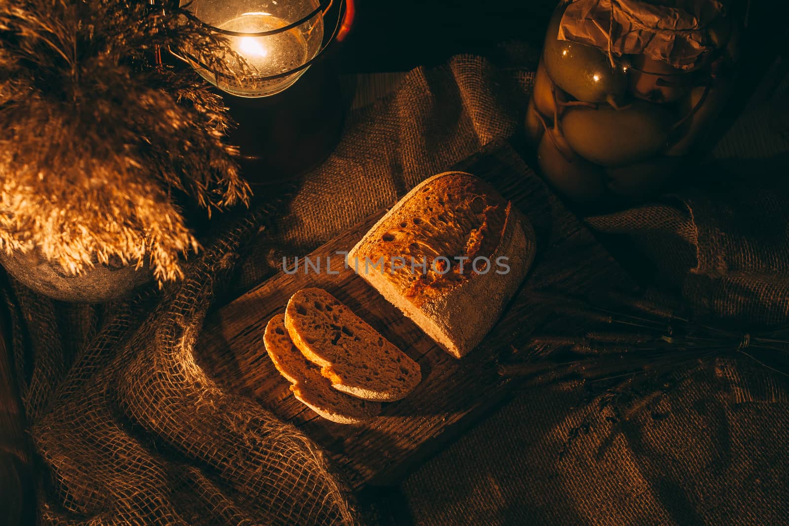 Sliced ​​bread with jam in the light of candles on a wooden board. Rustic atmosphere.Photo from the top