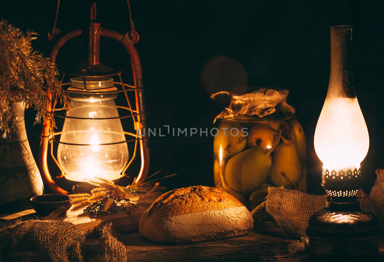 Homemade baked bread on a wooden board in warm light from gas la by Opikanets