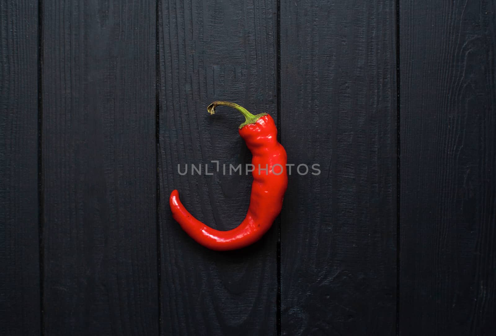 Hot red pepper on a black wooden matte background