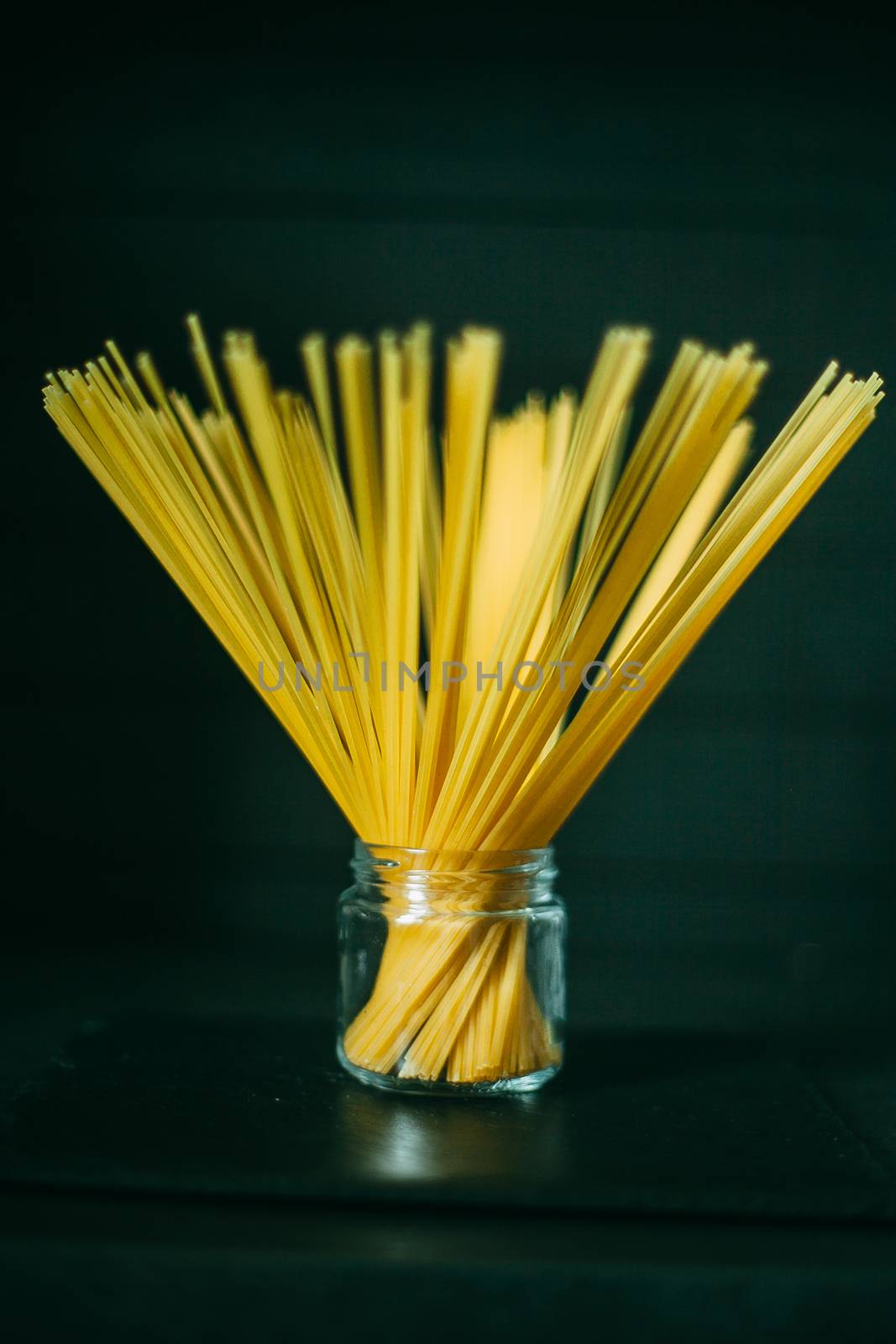 Unfolded spaghetti in a jar on a black wooden background