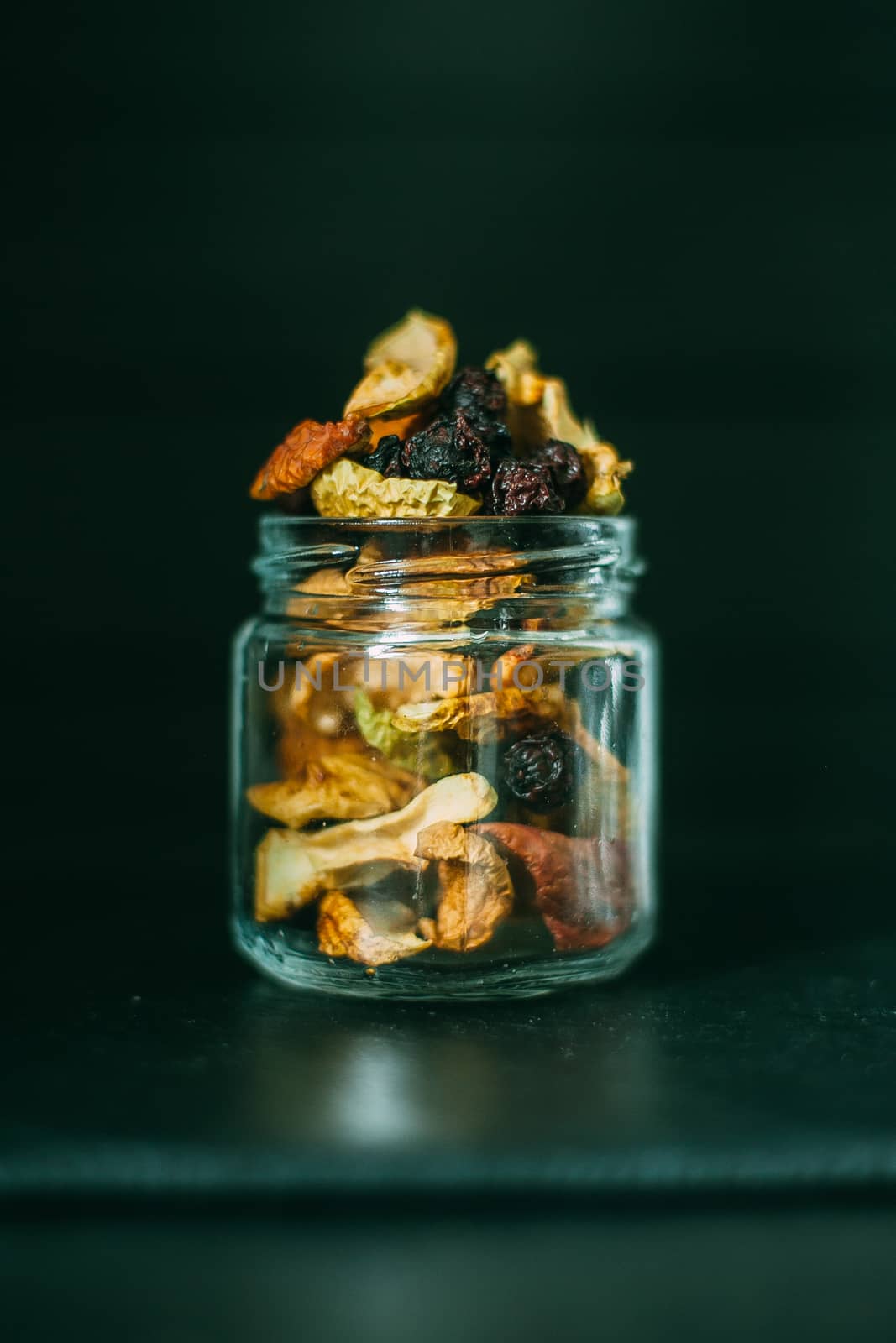 Dried fruits on a black background in a transparent jar by Opikanets