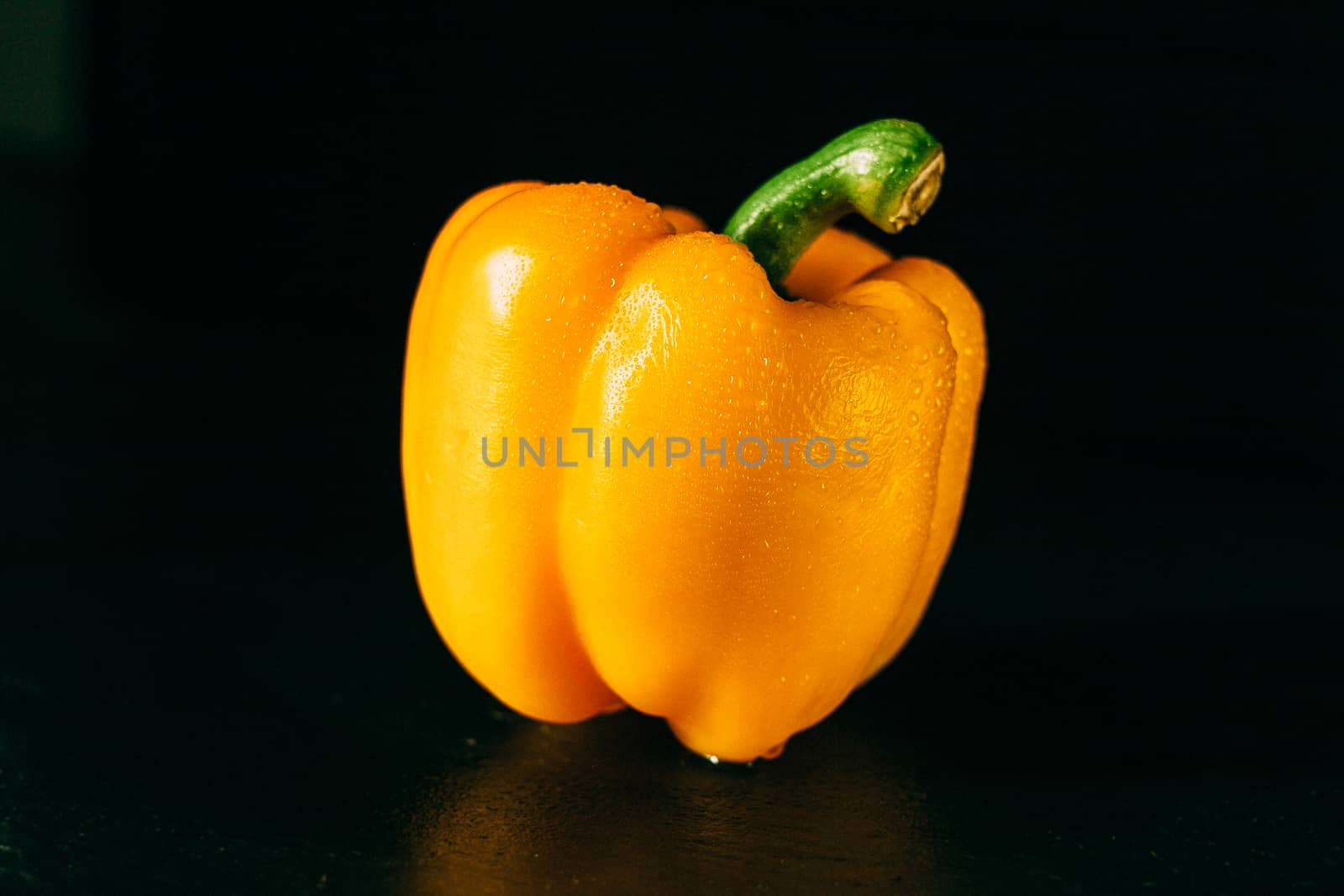 Yellow bell pepper with water droplets on a black background by Opikanets