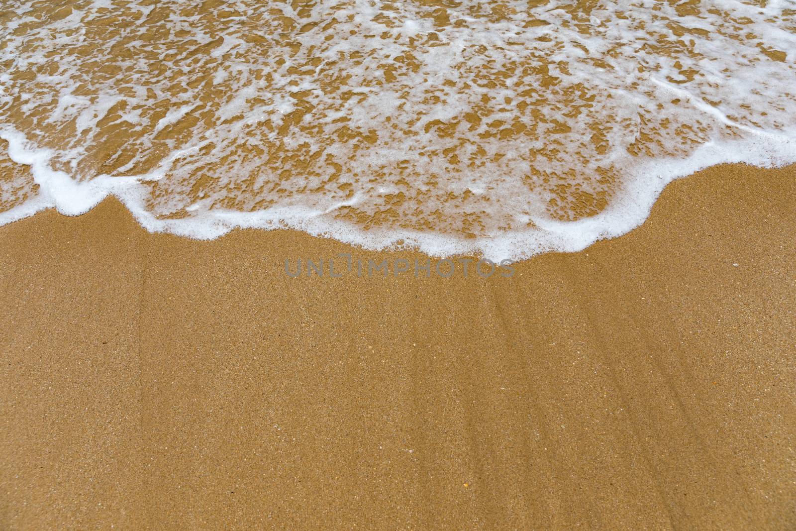 Blue ocean wave on sandy beach. Soft wave of blue ocean on sandy beach. Background. Top view of Beautiful beach with tranquil wave, sea and ocean background, summer vacation concept. 