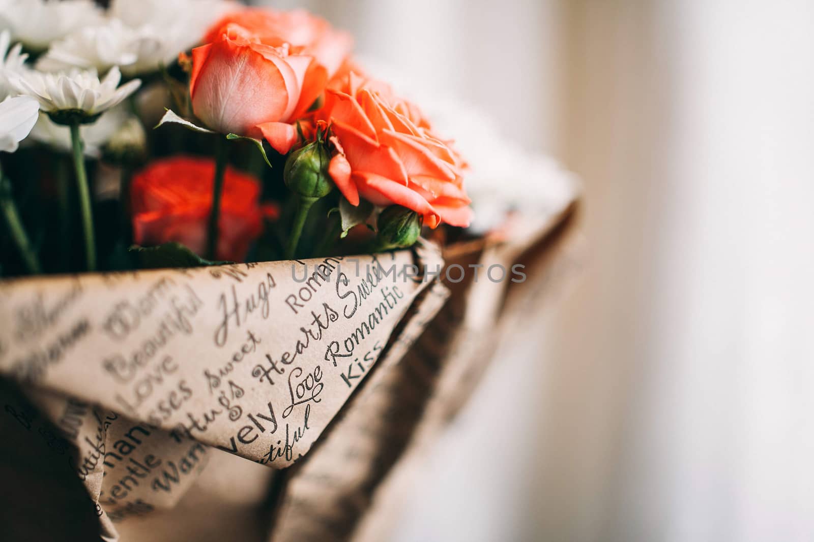 Bouquet of pink roses and white asters wrapped in paper. Close-up photo with copy space.