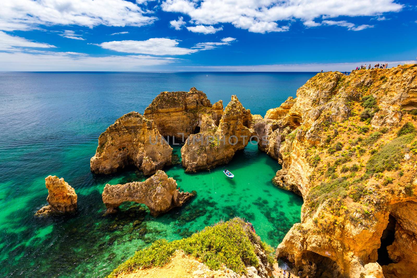 Panoramic view, Ponta da Piedade near Lagos in Algarve, Portugal. Cliff rocks and tourist boat on sea at Ponta da Piedade, Algarve region, Portugal. Ponta da Piedade, Algarve region, Portugal.