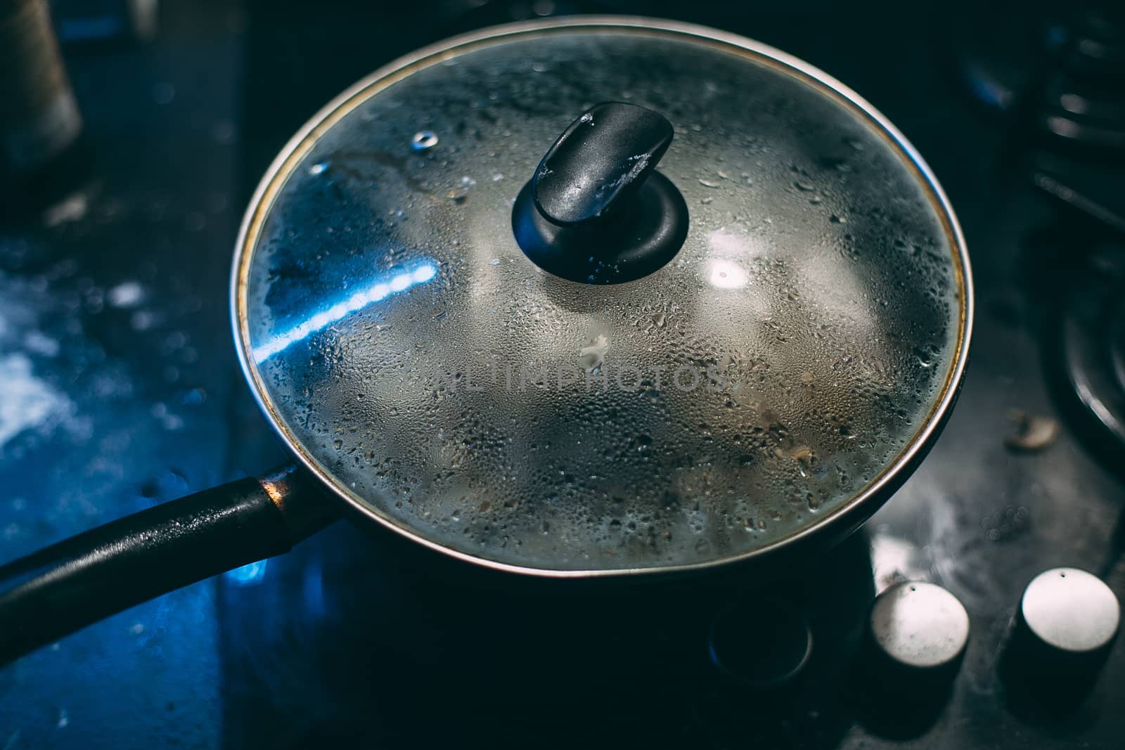 Black pan with a transparent lid on fire. Black plate