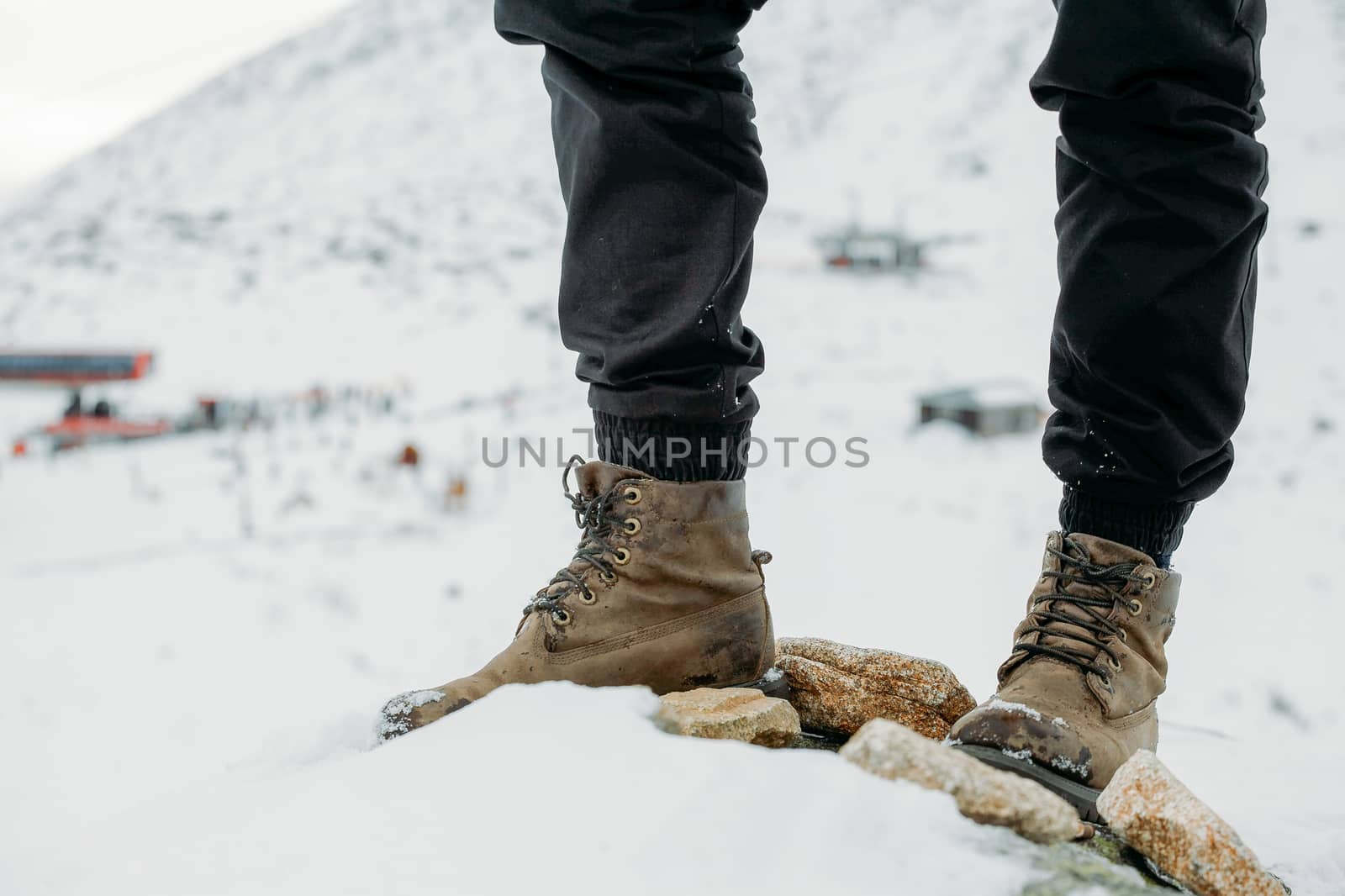 Feet in boots on a background of snowy mountains after a long wa by Opikanets