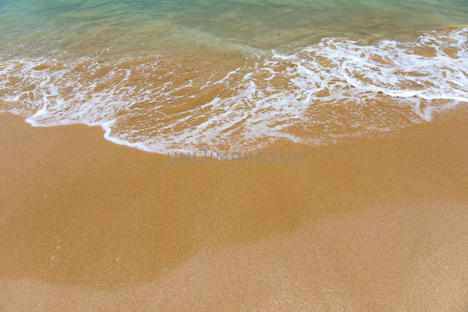 Blue ocean wave on sandy beach. Soft wave of blue ocean on sandy beach. Background. Top view of Beautiful beach with tranquil wave, sea and ocean background, summer vacation concept. 