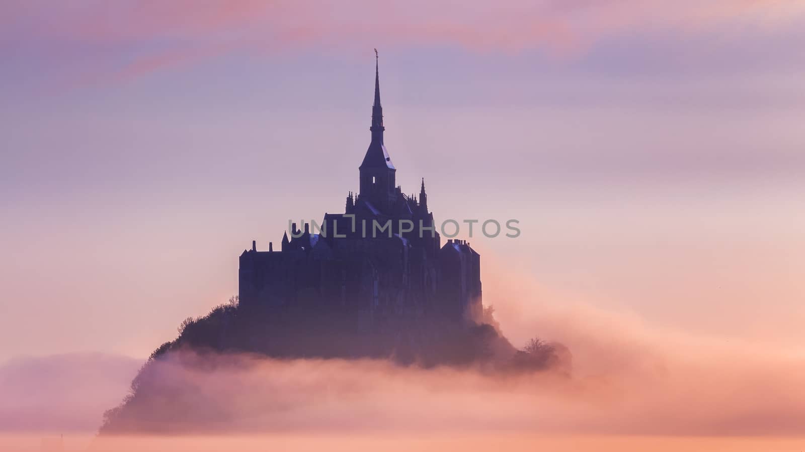 Panoramic view of famous Le Mont Saint-Michel tidal island in beautiful sunrise foggy light, Normandy, northern France