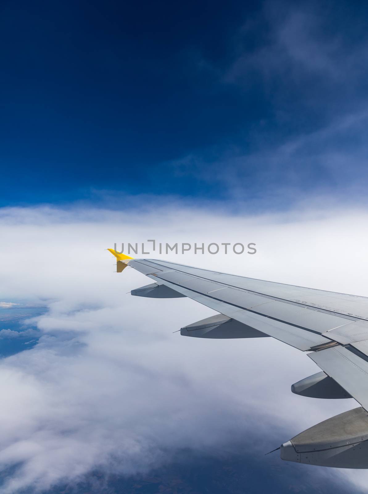Airplane windows view above the earth on landmark down. View from an airplane window over a wing flying high above farmlands and fields. View from window of plane airplane flying.