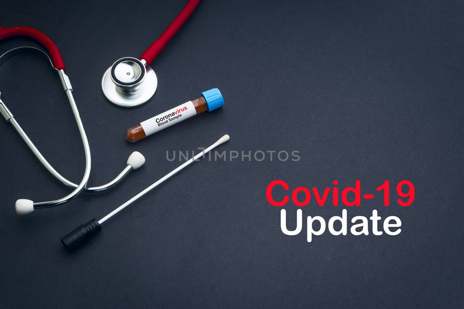 COVID-19 UPDATE text with stethoscope, blood sample vacuum tube and medical swabs on black background by silverwings