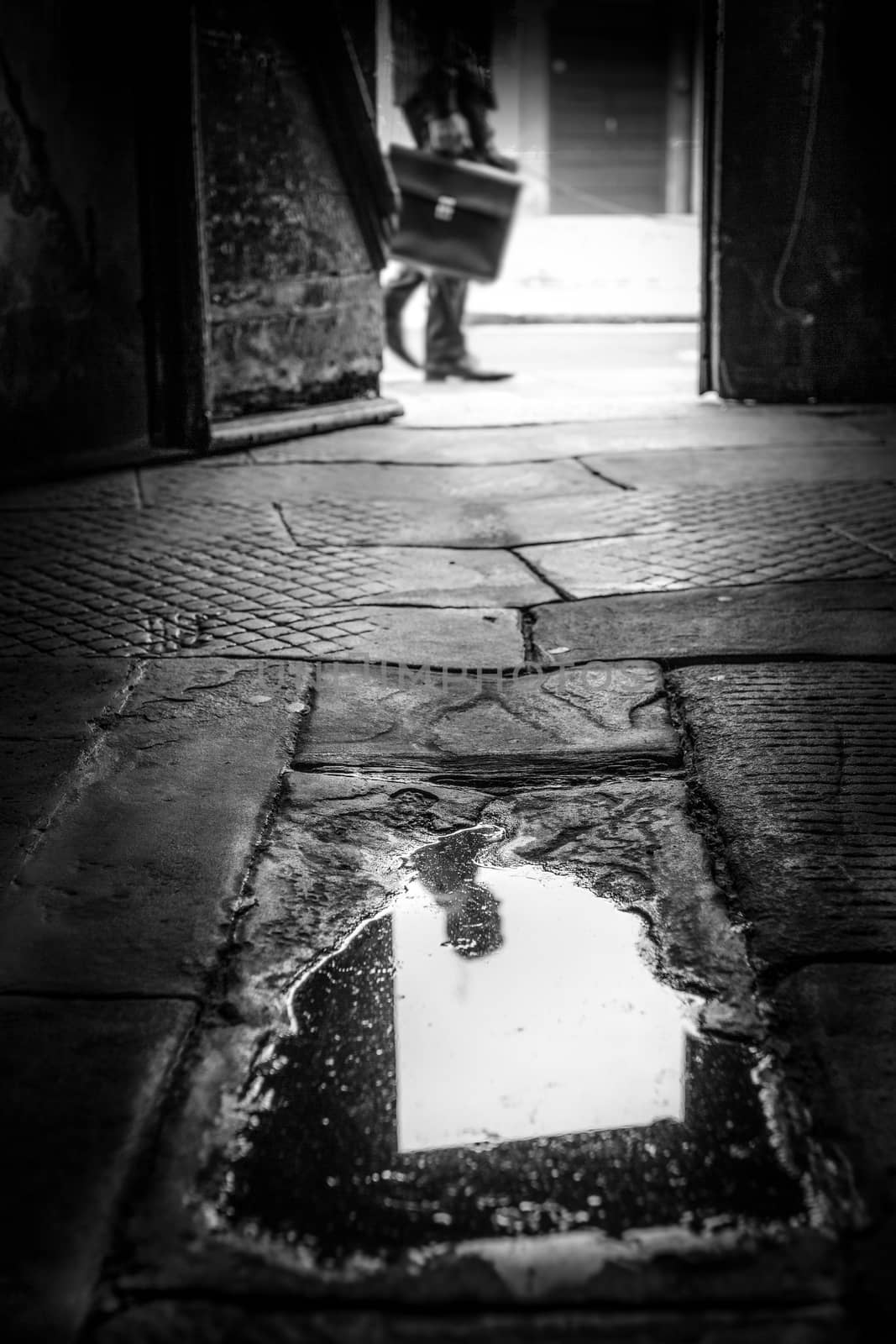 The head of a business man is reflected in a puddle.