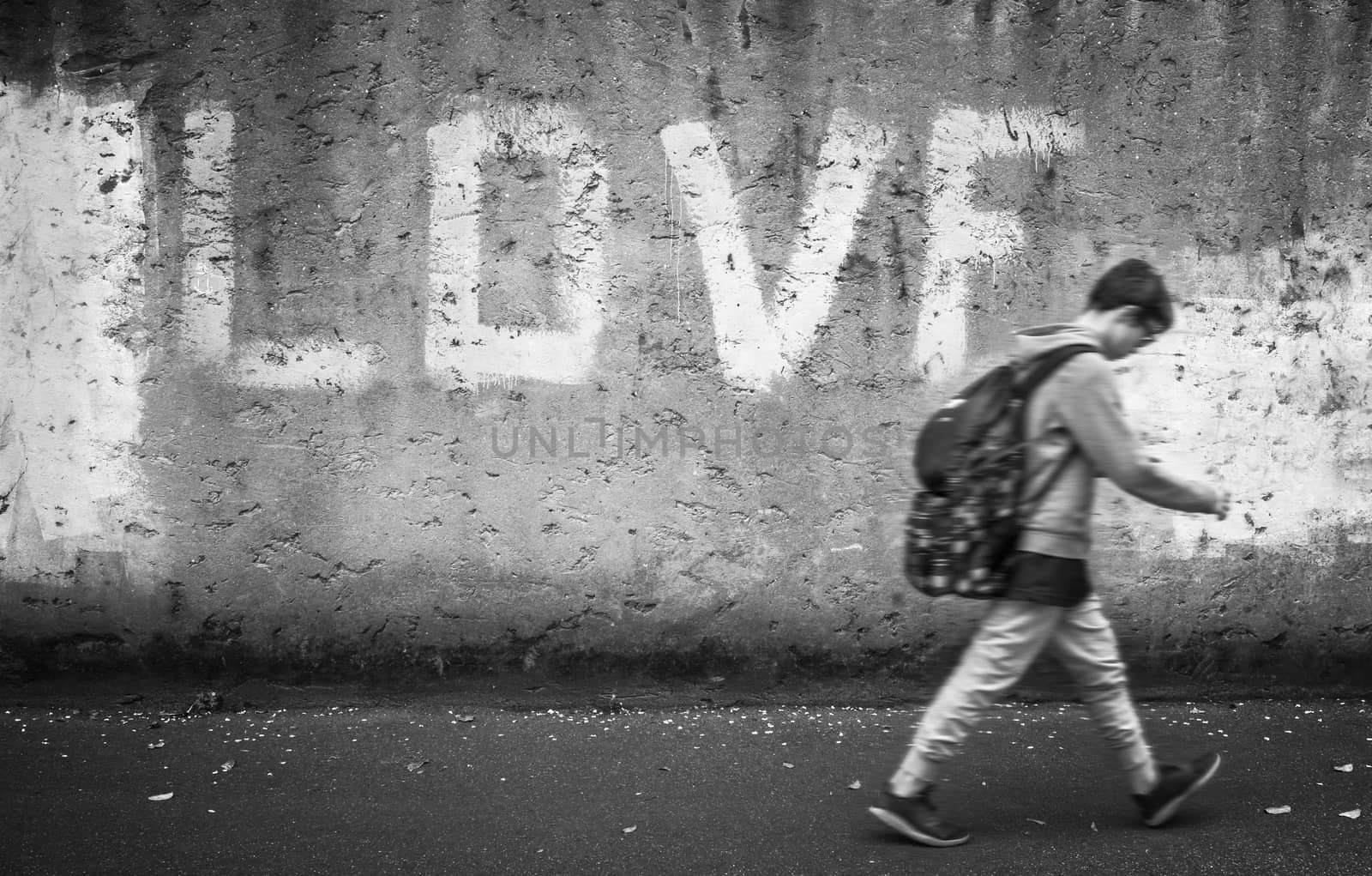 A schoolboy walking down the street with head bowed; on the wall stands the inscription "LOVE".