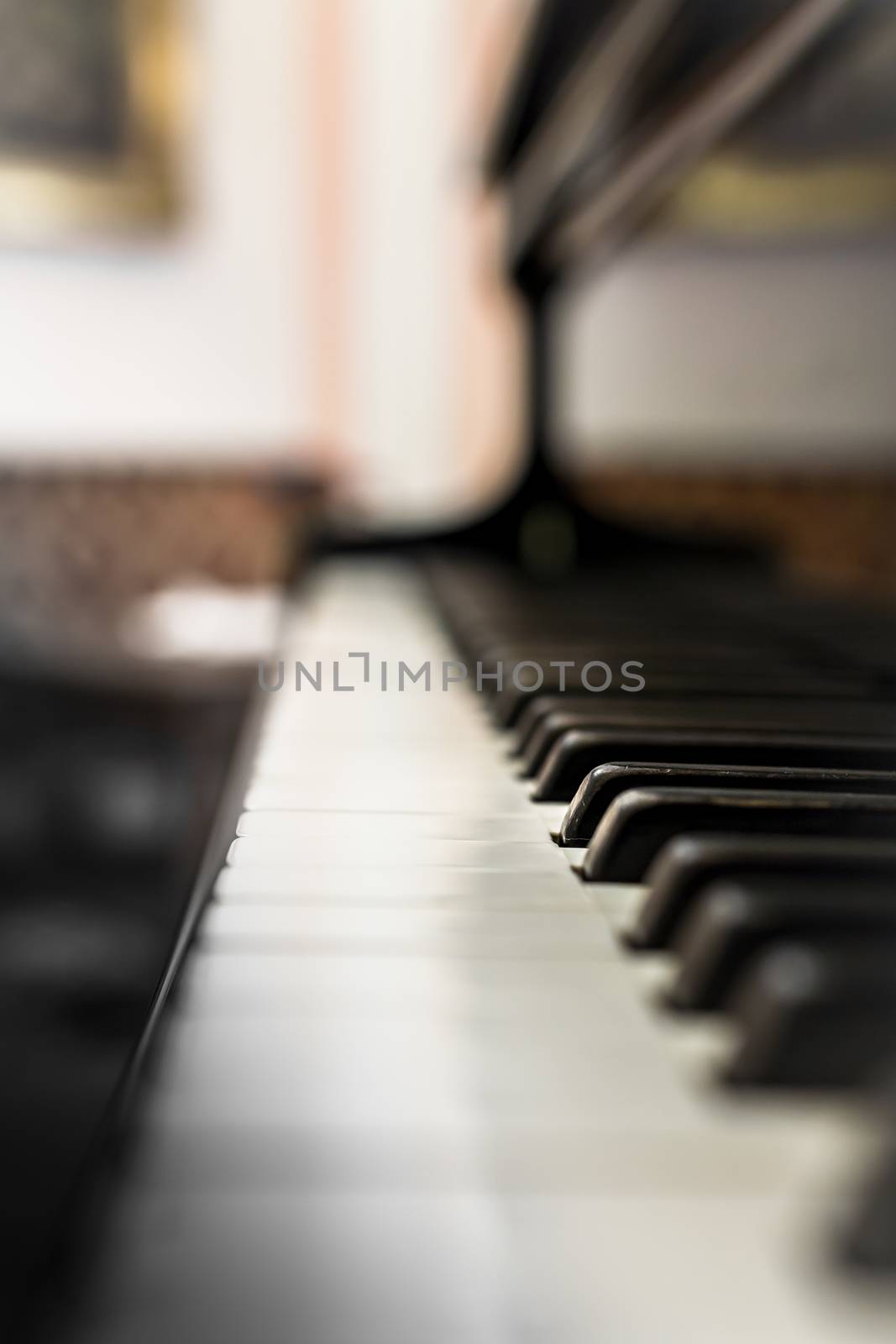 Old Piano keyboard with selective focus, behind a blurred background.