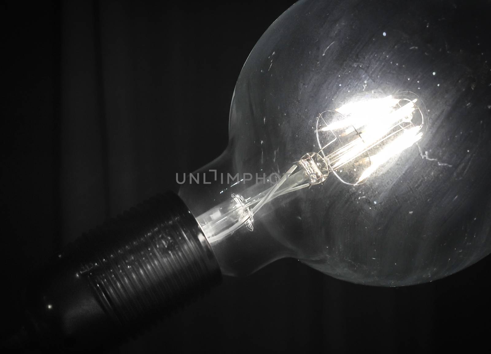A vintage style glowing lightbulb, illuminate the dark room.