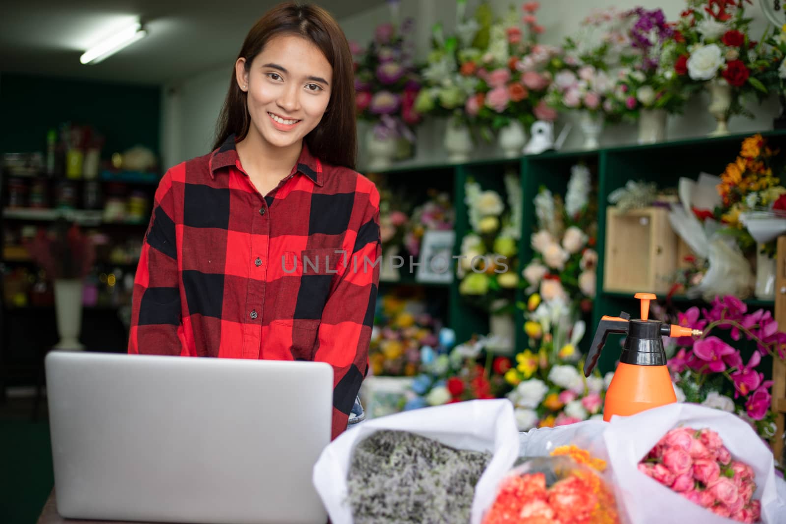 Asian women florists using notebook for working and smiling in flower shop