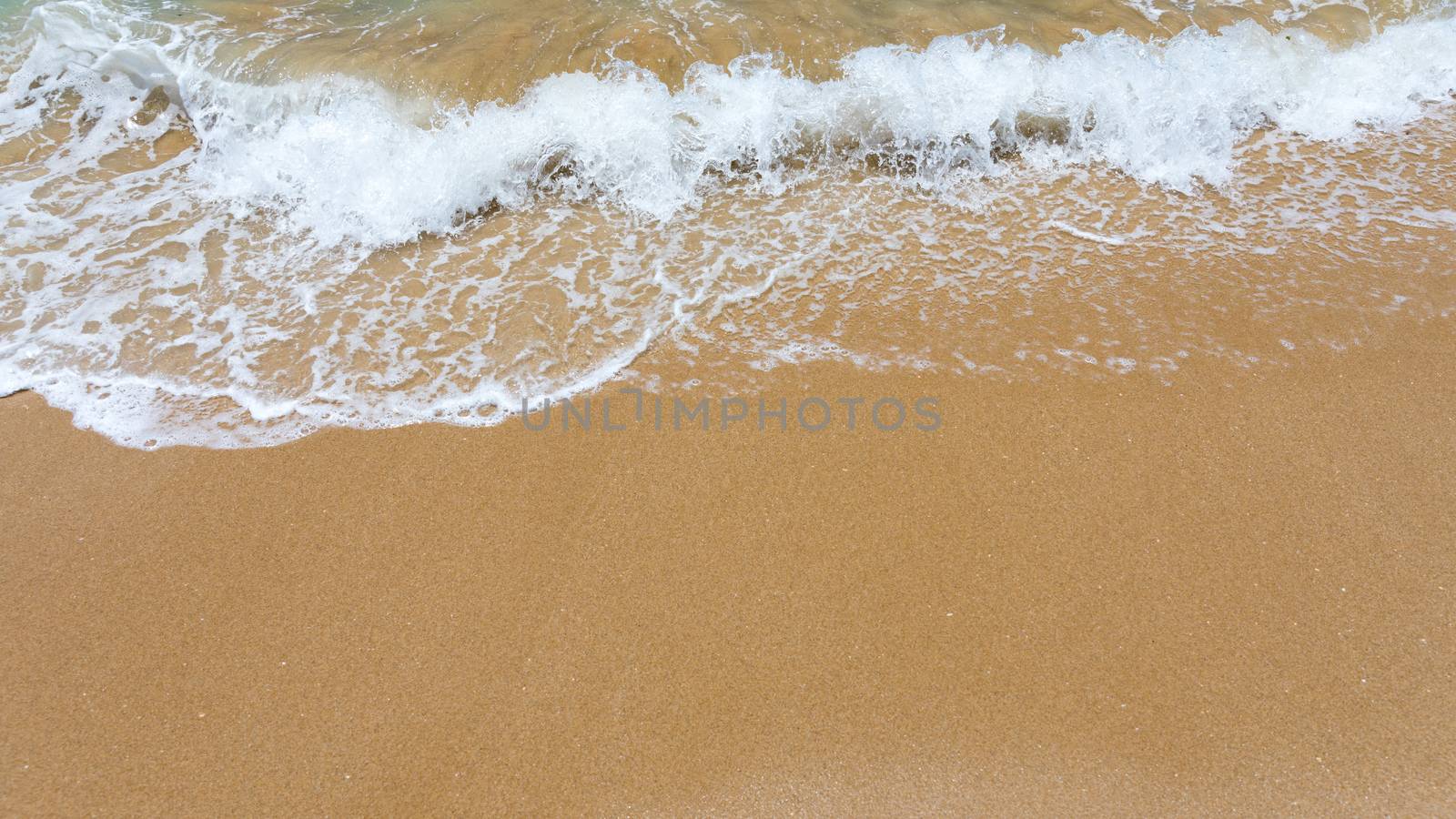 Blue ocean wave on sandy beach. Soft wave of blue ocean on sandy beach. Background. Top view of Beautiful beach with tranquil wave, sea and ocean background, summer vacation concept. 