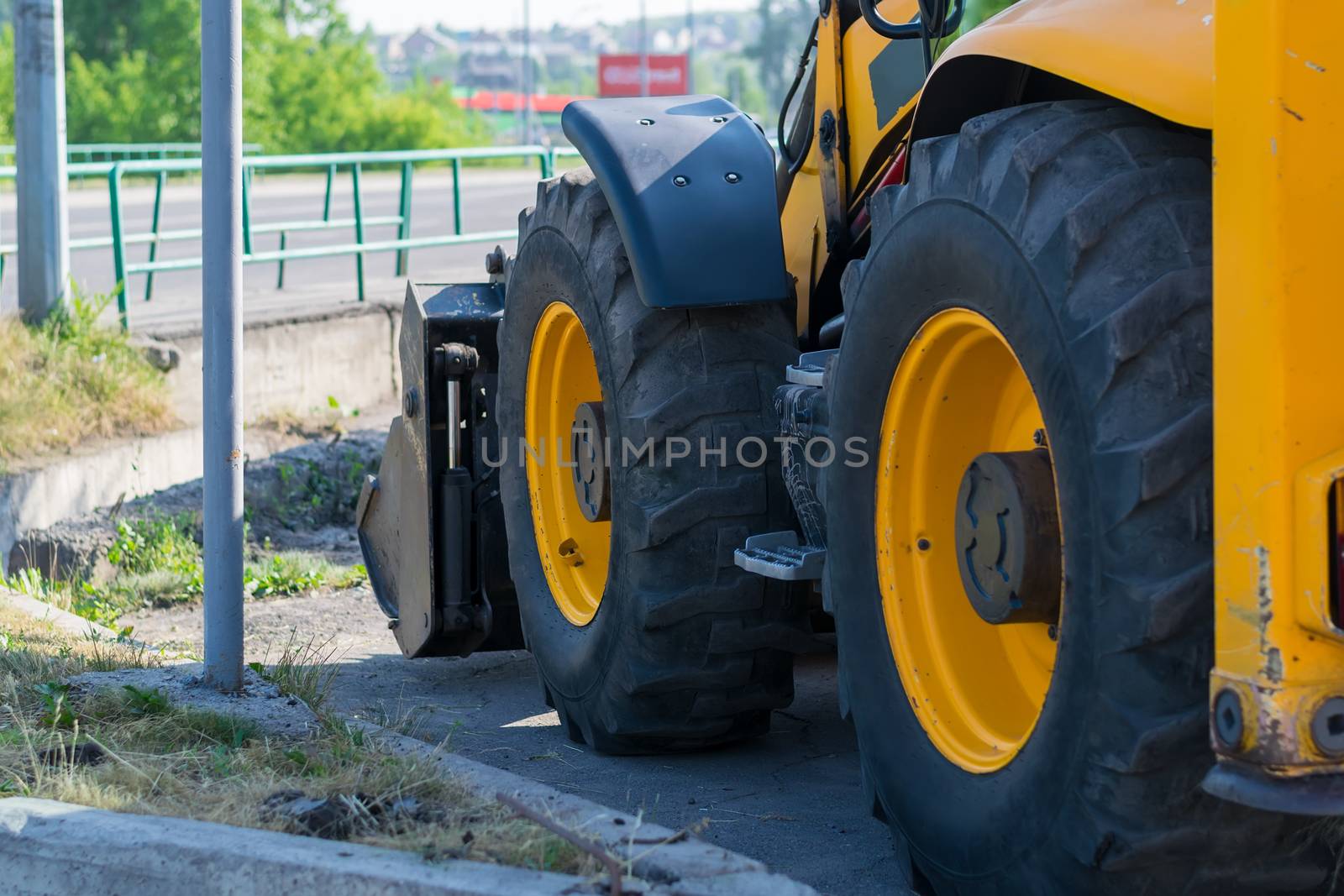 huge tractor wheels, grader on the side of the city street near the road by jk3030