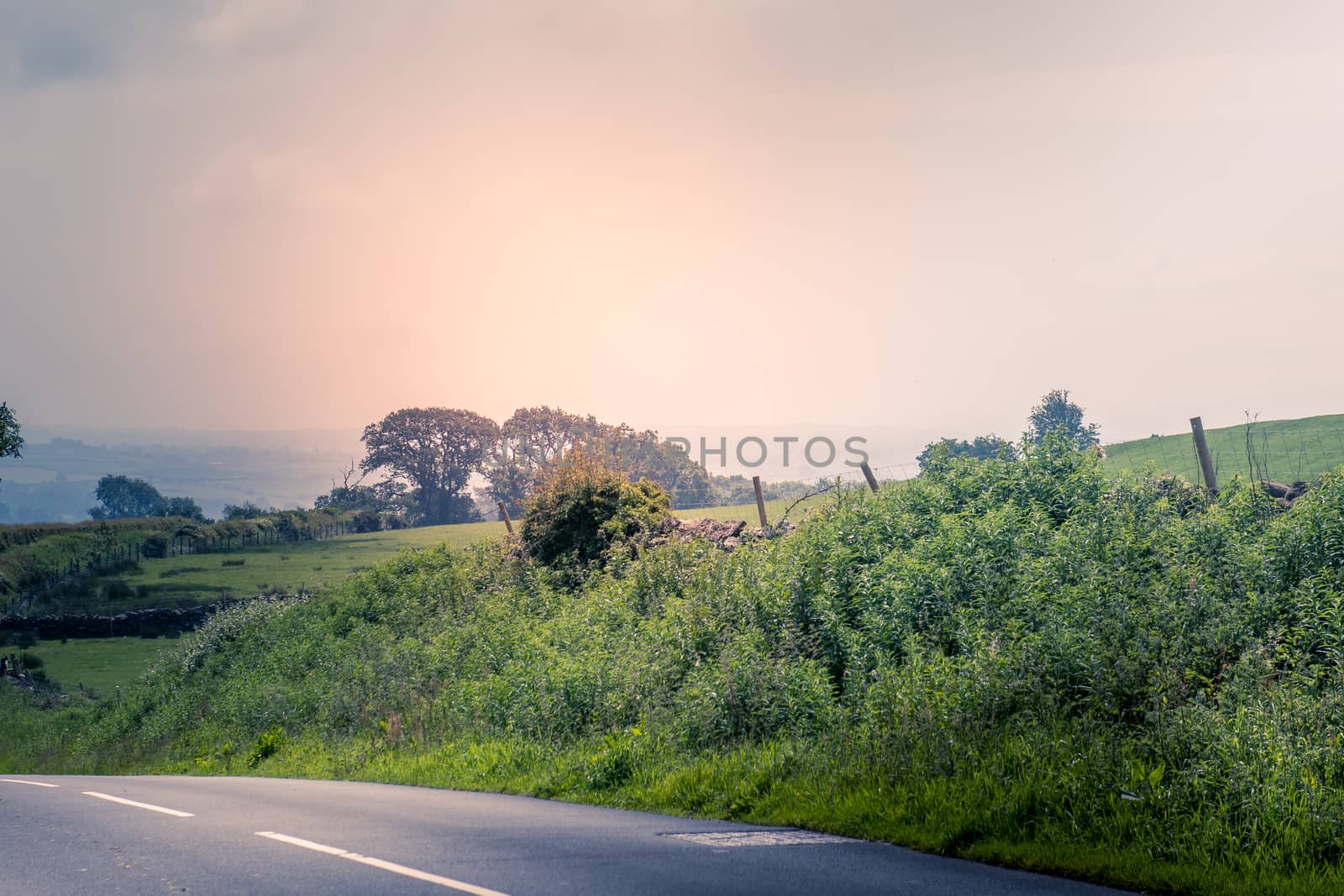 curved road in middle of rural Engalnd with dry stone walls and trees by paddythegolfer