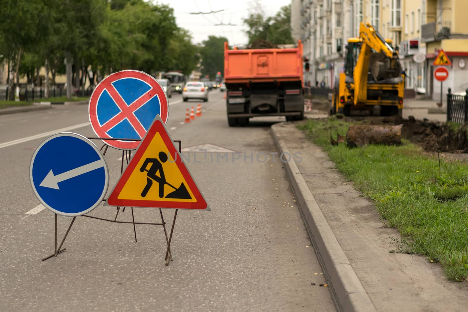 Road signs, detour, road repair on street background, truck and excavator digging hole