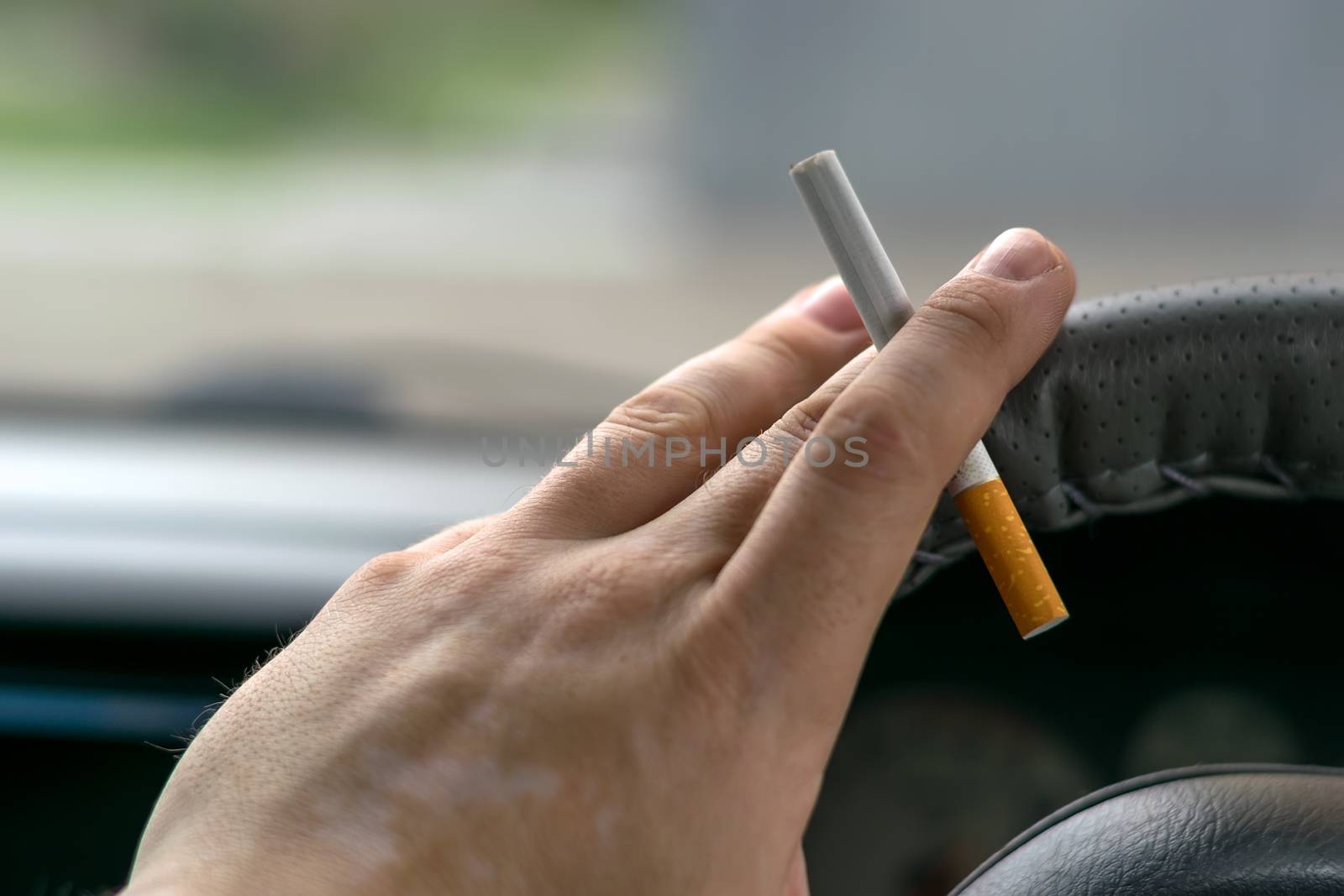 close-up, the hand of the driver of the car with skin disease "vitiligo" holds a cigarette